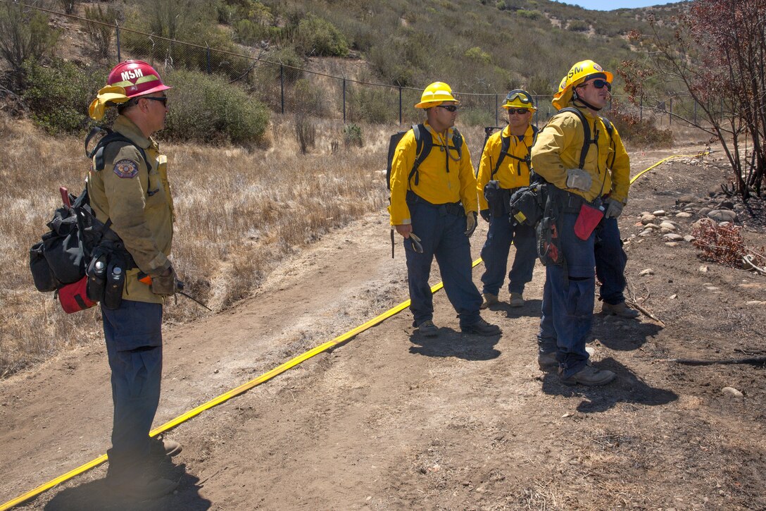 Capt. Danny Rivas, left, fire captain and Division “A” leader with the Miramar Fire Department, talks to his team during the wildland firefighting exercise with 3rd Marine Aircraft Wing aviators aboard Marine Corps Air Station Miramar, Calif., Aug. 14. Aviators and firefighters worked together to fight a simulated fire in order to build familiarity and a foundation in communication for future use while fighting fires.