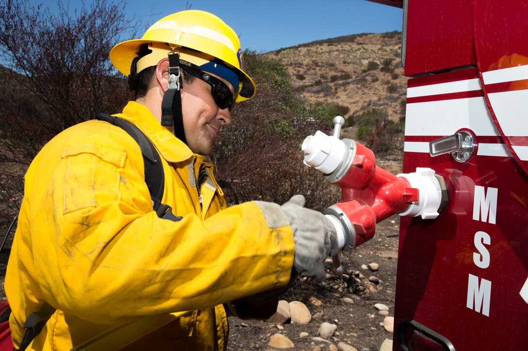 Brian Cato, a firefighter with the Miramar Fire Department, disassembles a fire hose after the wildland firefighting exercise with 3rd Marine Aircraft Wing aviators aboard Marine Corps Air Station Miramar, Calif., Aug. 14. Aviators and firefighters worked together to fight a simulated fire in order to build familiarity and a foundation in communication for future use while fighting fires.