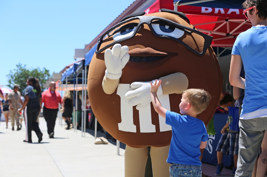 Sam, four, waves to a mascot during a vendor fair hosted by Marine Corps Community Services, at Camp Pendleton, Calif., Aug. 15. Thirty vendors participated in the two-hour event, which was held to enhance sales for the Country Store and raise awareness about its services. The store is in Camp Pendleton's Mainside area and hosts a number of restaurants, a beverage shop, a grocery store and tailoring services. (U.S. Marine Corps photo by Lance Cpl. Shaltiel Dominguez/ Released)