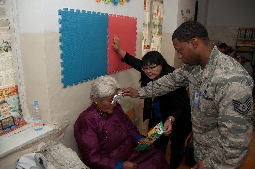 Tech. Sgt. Destin Huey, an optometry technician assigned to the 51 Aerospace Medicine Squadron, and a Mongolian interpreter perform an eye exam as part of Pacific Angel 14-4 in Bulgan Mongolia, Aug. 15, 2014. Operation PACANGEL helps cultivate common bonds and foster goodwill between the U.S., Mongolia and regional nations by conducting multilateral humanitarian assistance and civil military operations. (U.S. Air Force photo by Staff Sgt. William Banton/Released)