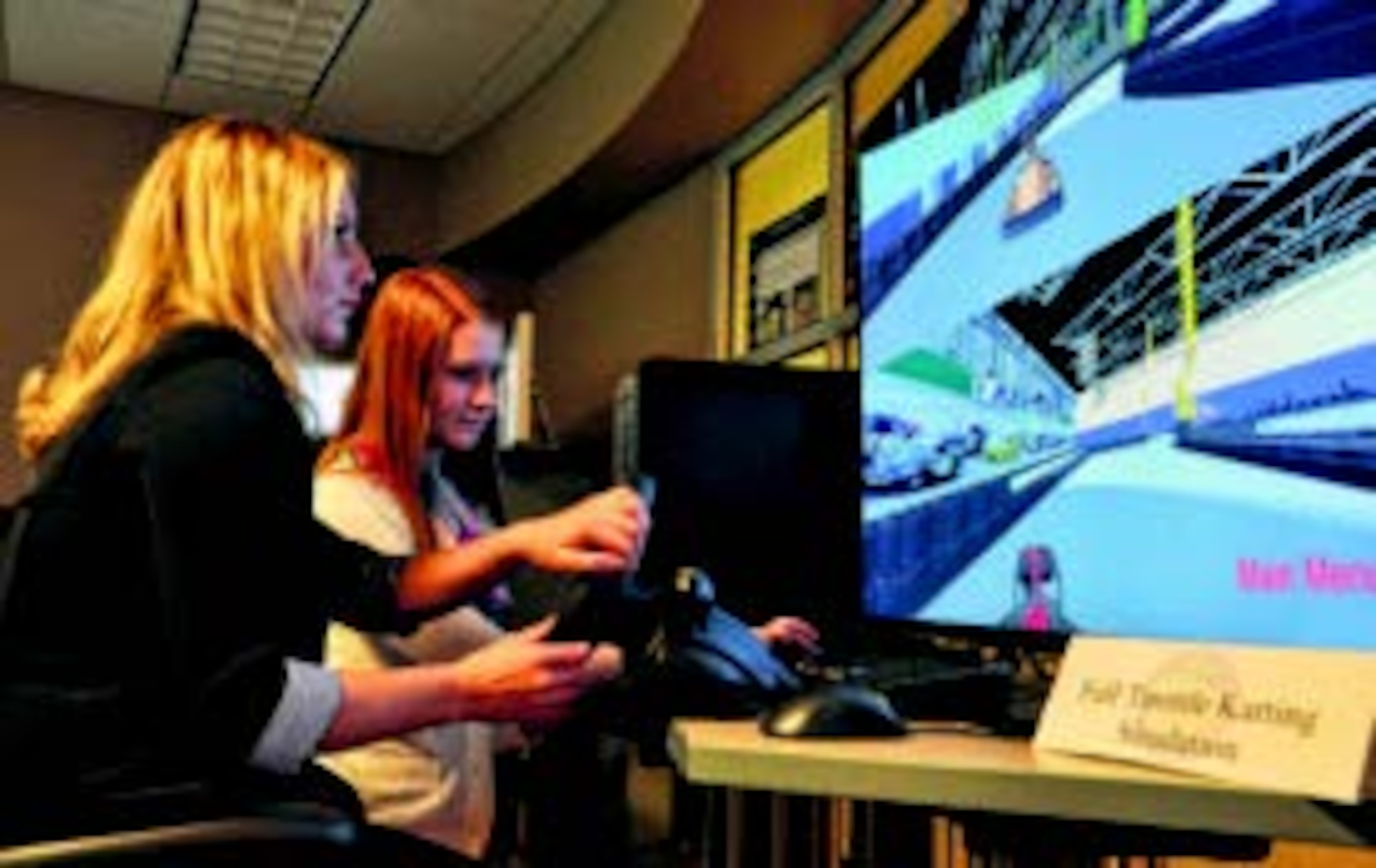 Air Force Research Laboratory Gaming Research Integration for Learning Lab interns Macy Fraylick and Lizzie Adams demonstrate the Full Throttle Karting simulation tool Aug. 7 at the Wright Brothers Institute s Tec^Edge Innovation and Collaboration Center in Dayton. (Air Force photo by Michele Eaton)