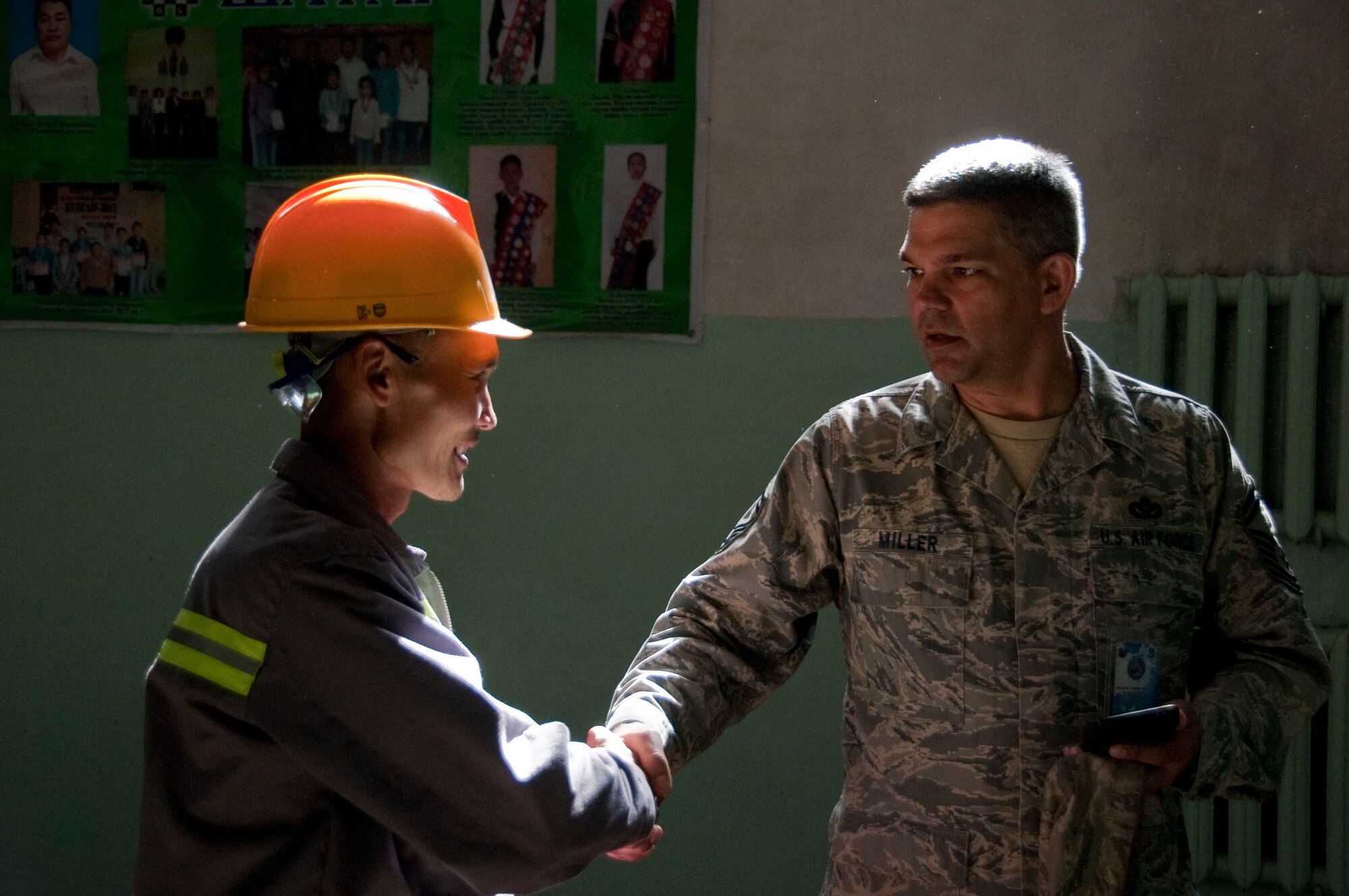 Mongolian Armed Forces Sgt. Erdentsgot Batchuluun, a MAF electrician (left), introduces himself to U.S. Air Force Senior Master Sgt. Sandy Miller, senior engineering lead assigned to 354th Civil Engineer Squadron at Eielson Air Force Base, Alaska, in an elementary during Operation Pacific Angel 14-4, Bulgan, Mongolia, Aug. 12, 2014. Operation PACANGEL helps cultivate common bonds and fosters goodwill between the U.S., Mongolia and regional nations by conducting multilateral humanitarian assistance and civil military operations. (U.S. Air Force photo by Staff Sgt. William Banton/Released)