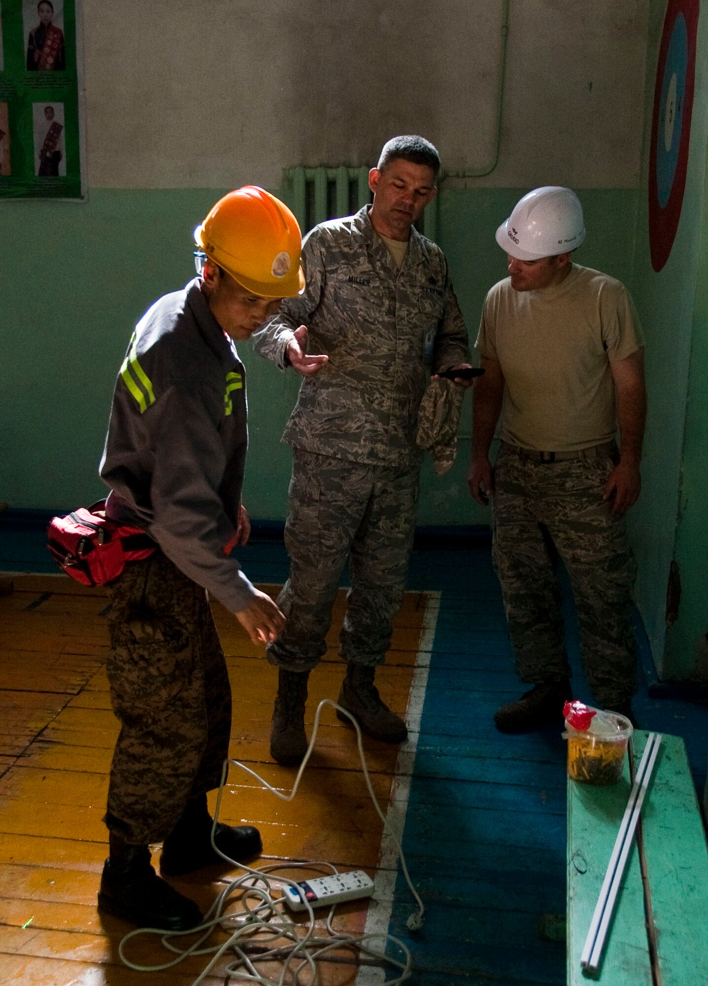Mongolian Armed Forces Sgt. Erdentsgot Batchuluun, a MAF electrician (left), reviews equipment as U.S. Air Force Senior Master Sgt. Sandy Miller (center) and Tech. Sgt. Brede Grorud, civil engineers assigned to the 354th Civil Engineer Squadron at Eielson Air Force Base, Alaska, discuss the electrical system in a elementary school in Bulgan, Mongolia, Aug. 12, 2014. Operation Pacific Angel helps cultivate common bonds and fosters goodwill between the U.S., Mongolia and regional nations by conducting multilateral humanitarian assistance and civil military operations. (U.S. Air Force photo by Staff Sgt. William Banton/Released)