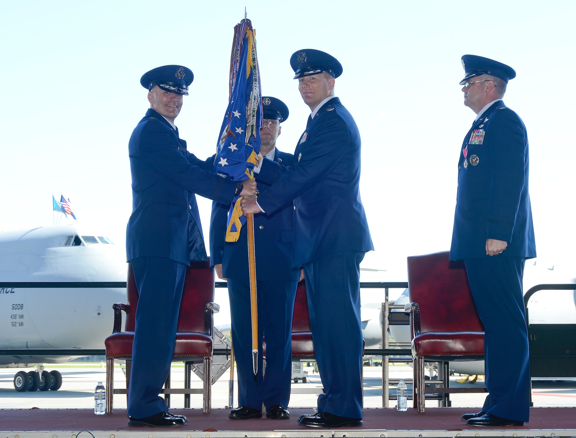 Col. Michael W. Grismer Jr., center, assumes command of the 436th Airlift Wing by taking the guidon from Lt. Gen. Carlton D. Everhart II, 18th Air Force commander. Command Chief Master Sgt. Stanley Cadell is shown in the background along with outgoing commander Col. Richard G. Moore Jr., Aug. 15, 2014, at Dover Air Force Base, Del. (U.S. Air Force photo/Greg L. Davis) 