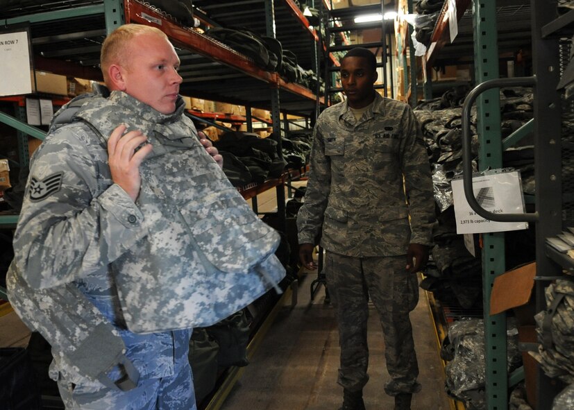 U.S. Air Force Staff Sgt. Richard Ebensberger, 7th Bomb Wing unit deployment manager, tries on an improved outer tactical vest so Senior Airman Trent Smith, 7th Logistics Readiness Squadron combat mobility journeyman, can ensure that it fits correctly Aug. 13, 2014 in the combat mobility warehouse at Dyess Air Force Base, Texas. Deployments differ in location and reporting guidelines, which determine the specific gear and amount of equipment each individual is issued. (U.S. Air Force photo by Senior Airman Shannon Hall/Released)