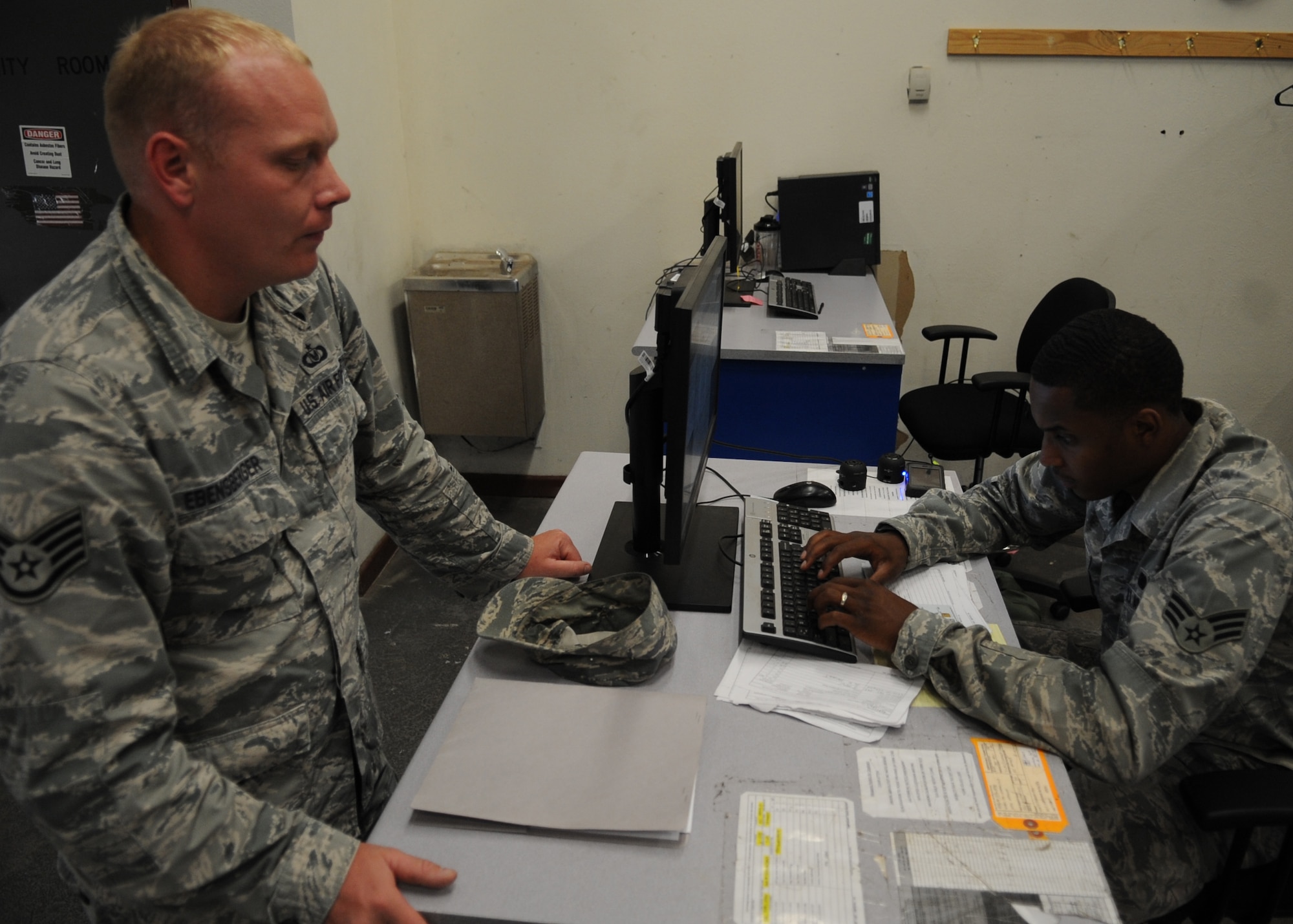 U.S. Air Force Staff Sgt. Richard Ebensberger, 7th Bomb Wing unit deployment manager, waits while his information is input into a system by Senior Airman Trent Smith, 7th Logistics Readiness Squadron combat mobility journeyman, Aug. 13, 2014, in the combat mobility warehouse at Dyess Air Force Base, Texas. The Mobility Inventory Control and Accountability System offers visibility of all Dyess mobility equipment that is deployed and on-hand in the warehouse. (U.S. Air Force photo by Senior Airman Shannon Hall/Released)