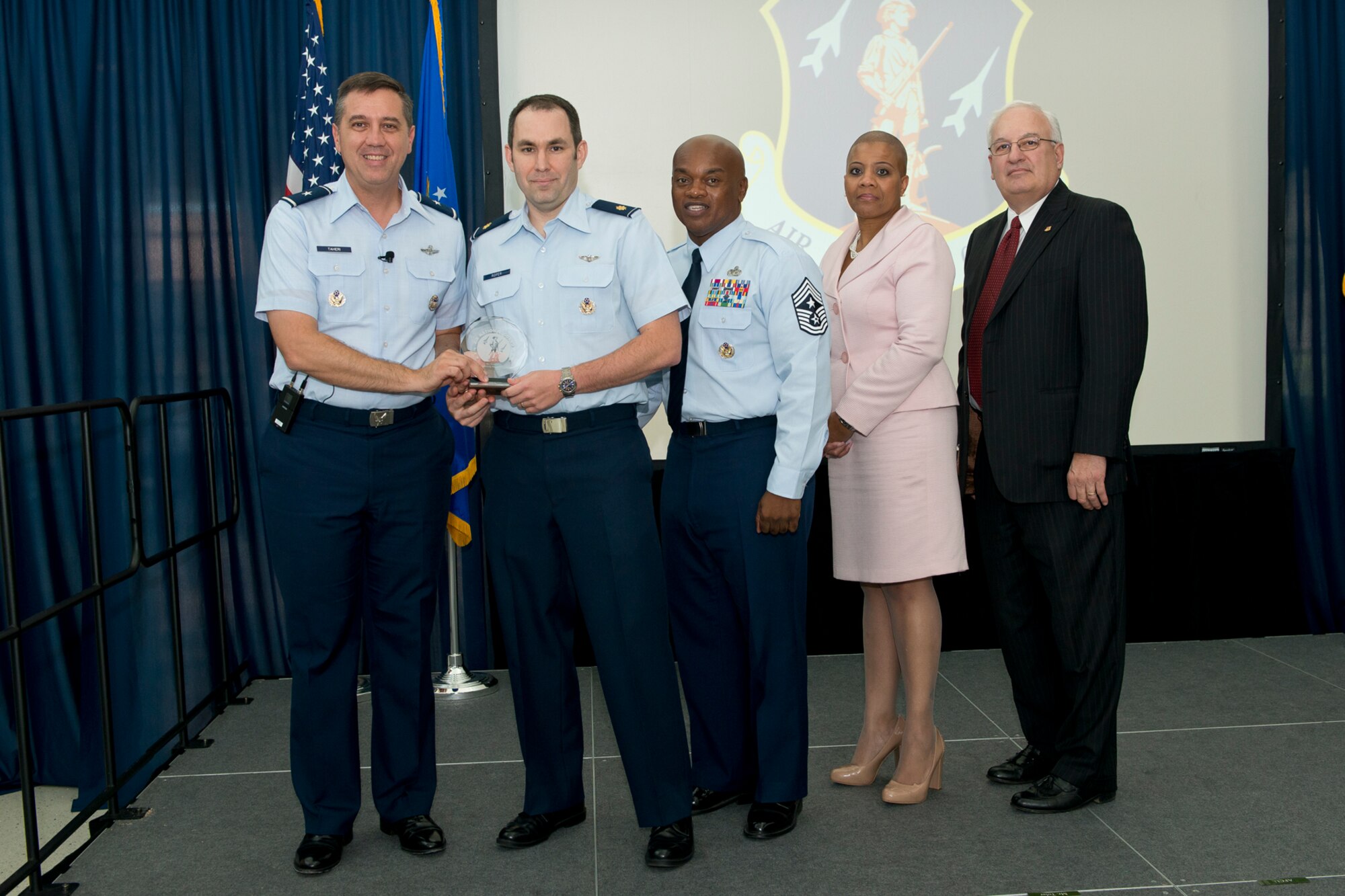 Brig. Gen. Michael R. Taheri, commander of the Air National Guard Readiness Center and Chief Master Sgt. Tony L. Whitehead, command chief master sergeant of the ANGRC, present the Field Grade Officer of the Quarter award to Maj. Drew D. Roper during the 2nd Quarter Awards Ceremony and Commander’s Call August 14, 2014. Rosalind Bishop, Joint Base Andrews branch manager of Andrews Federal Credit Union and Paul Ariente, president of the National Guard Bureau Alumni Association were sponsors for the event. (Air National Guard photo by Master Sgt. Marvin R. Preston/Released)