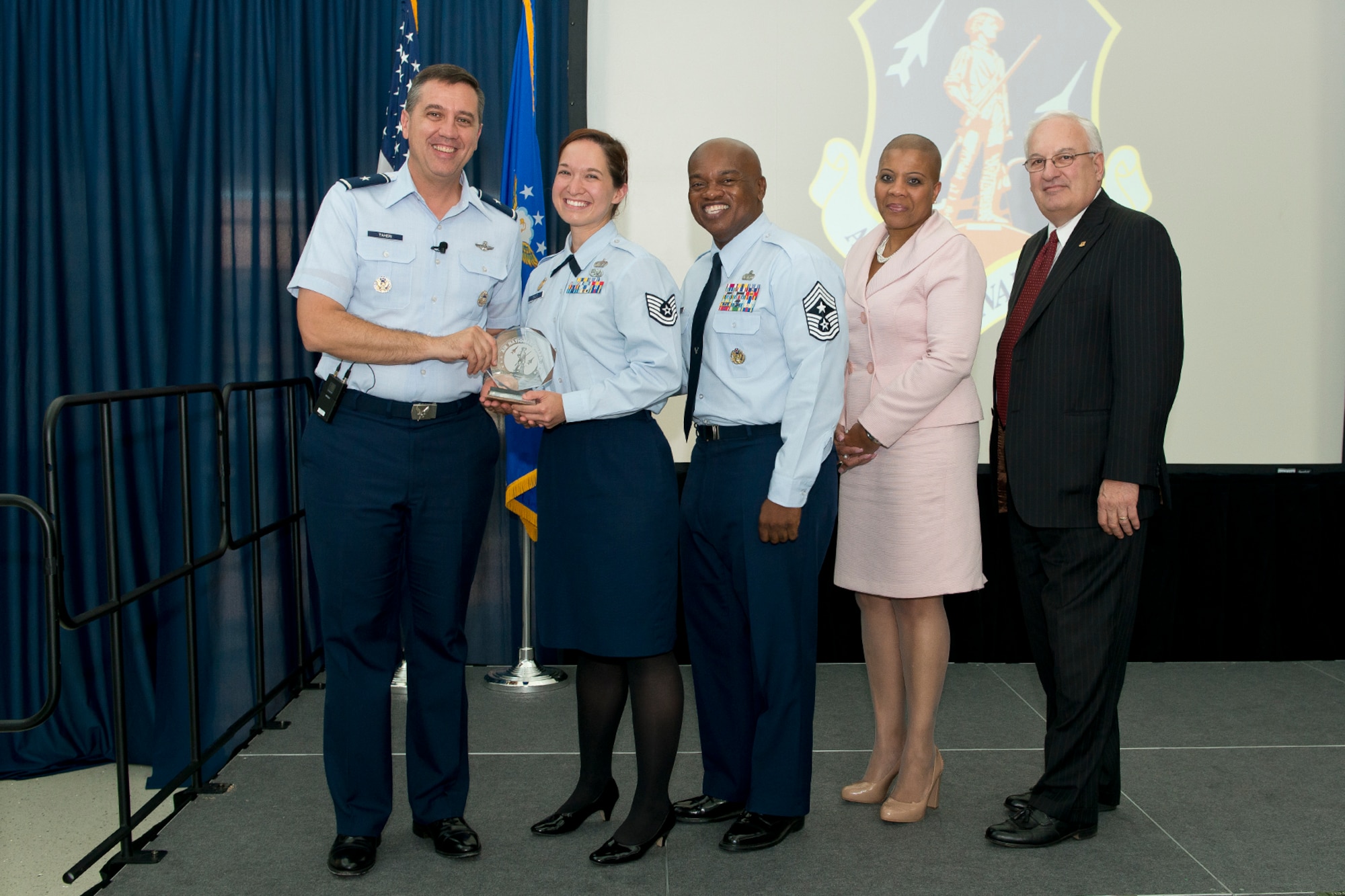 Brig. Gen. Michael R. Taheri, commander of the Air National Guard Readiness Center and Chief Master Sgt. Tony L. Whitehead, command chief master sergeant of the ANGRC, present the Non-Commissioned Officer of the Quarter award to Technical Sgt. Kristin N. Schultz during the 2nd Quarter Awards Ceremony and Commander’s Call August 14, 2014. Rosalind Bishop, Joint Base Andrews branch manager of Andrews Federal Credit Union and Paul Ariente, president of the National Guard Bureau Alumni Association were sponsors for the event. (Air National Guard photo by Master Sgt. Marvin R. Preston/Released)