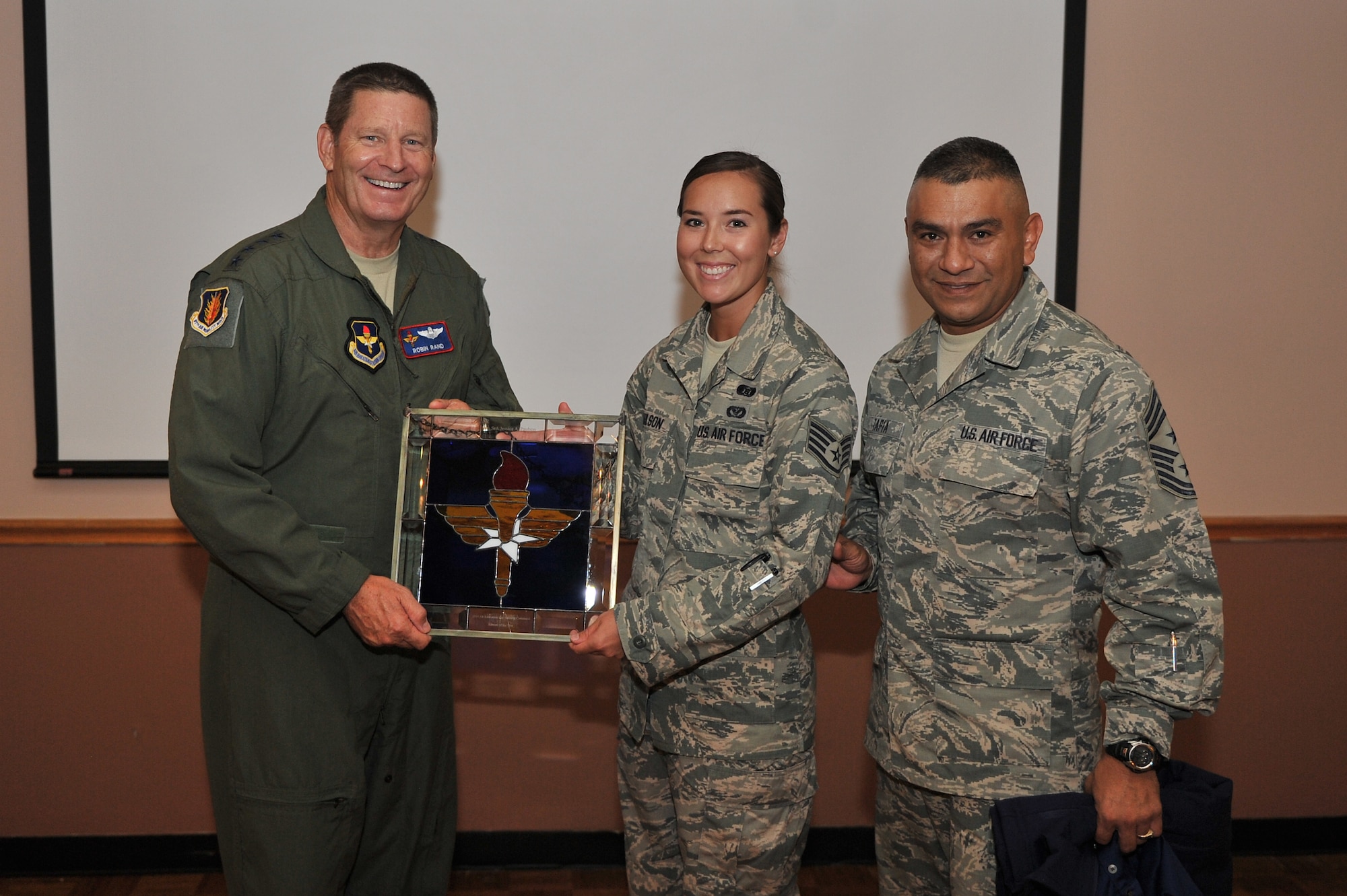 ALTUS AIR FORCE BASE, Okla. – U.S. Air Force Gen. Robin Rand, commander of Air Education and Training Command, and U.S. Air Force Chief Master Sgt. Gerardo Tapia, Air Education and Training Command command chief, present a gift to the 2014 AETC Outstanding Airman of the Year, Staff Sgt. Jessica Paulson, 97th Civil Engineering Squadron. Paulson was deployed as a Senior Airman when she earned the award.  (U.S. Air Force photo by Senior Airman Dillon Davis/Released)