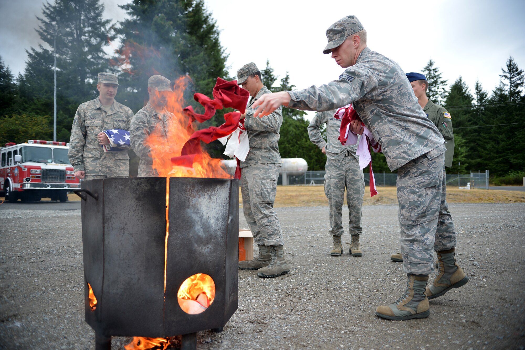 Members of the McChord Field Honor Guard throw pieces of a flag into a fire, Aug. 13, 2014, at Joint Base Lewis-McChord, Wash. The McChord Field Honor Guard had been collecting donated flags for several years prior to the ceremony. (U.S. Air Force photo/Airman 1st Class Keoni Chavarria)  