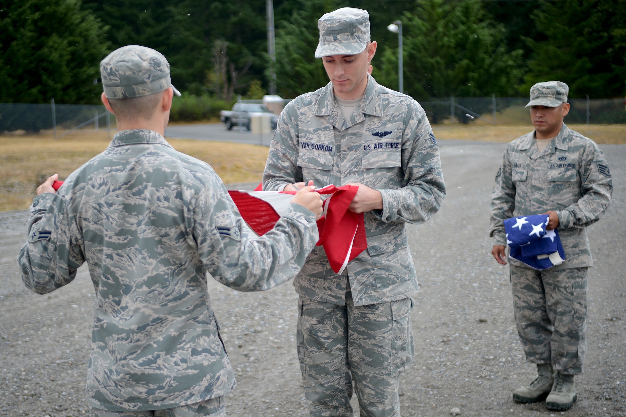 Airman 1st Class Austin Shupe and Senior Airman Steven Van Gorkom, McChord Field Honor Guard members, cut a flag while Staff Sgt. Eddson Vilca, McChord Field Honor Guard NCO in charge, holds a piece of a flag, Aug. 13, 2014, at Joint Base Lewis-McChord, Wash. During the ceremony, the stars on the flag were cut first, followed by the stripes. (U.S. Air Force photo/Airman 1st Class Keoni Chavarria)  