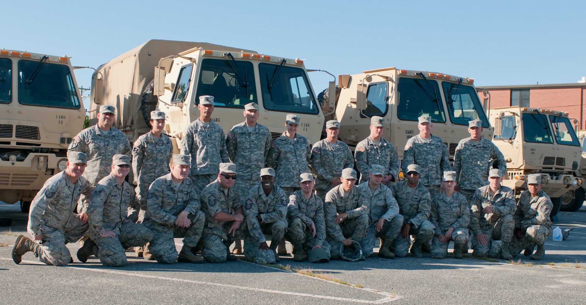 Airmen from the 102nd Intelligence Wing pose with members of the 1166th Transportation Company in front of light/medium tactical vehicles (LMTV) on Aug. 12, 2014 at Joint Base Cape Cod. The Mass. Air Guard airmen were receiving training from the Mass. Army Guard soldiers on the maintenance and operation of the LMTVs. (U.S. Air National Guard photo by Master. Sgt. Aaron Smith /Released)