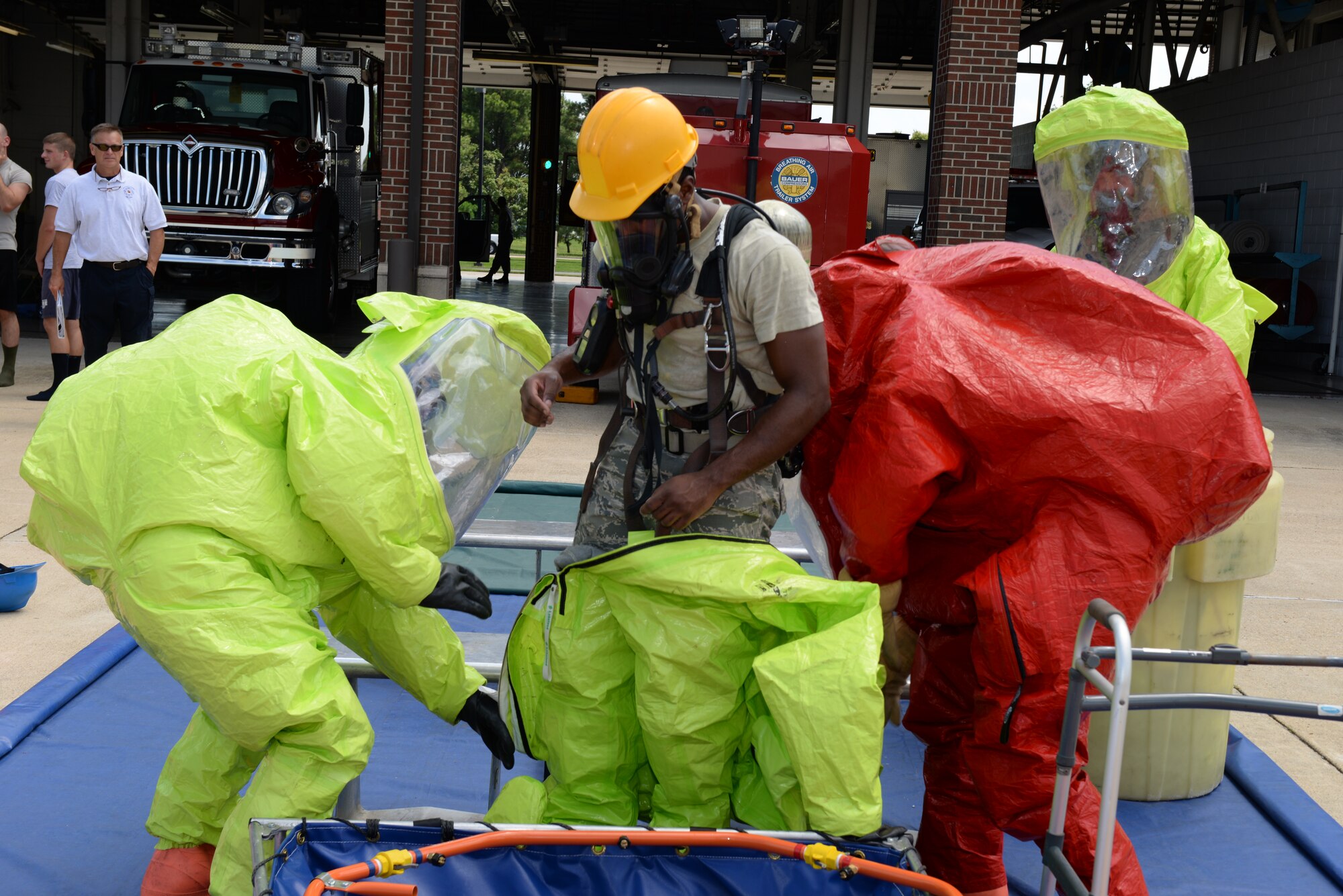 U.S. Service members work together to properly remove personal protective equipment during a two-week Hazardous Material Awareness and Operations Training Course at Langley Air Force Base, Va., Aug. 13, 2014. Students were taught different techniques for dealing with hazardous substances, including identification, what type of personal protective equipment is needed for specific circumstances and the order of controlling a spill. (U.S. Air Force photo by Senior Airman Connor Estes/Released)