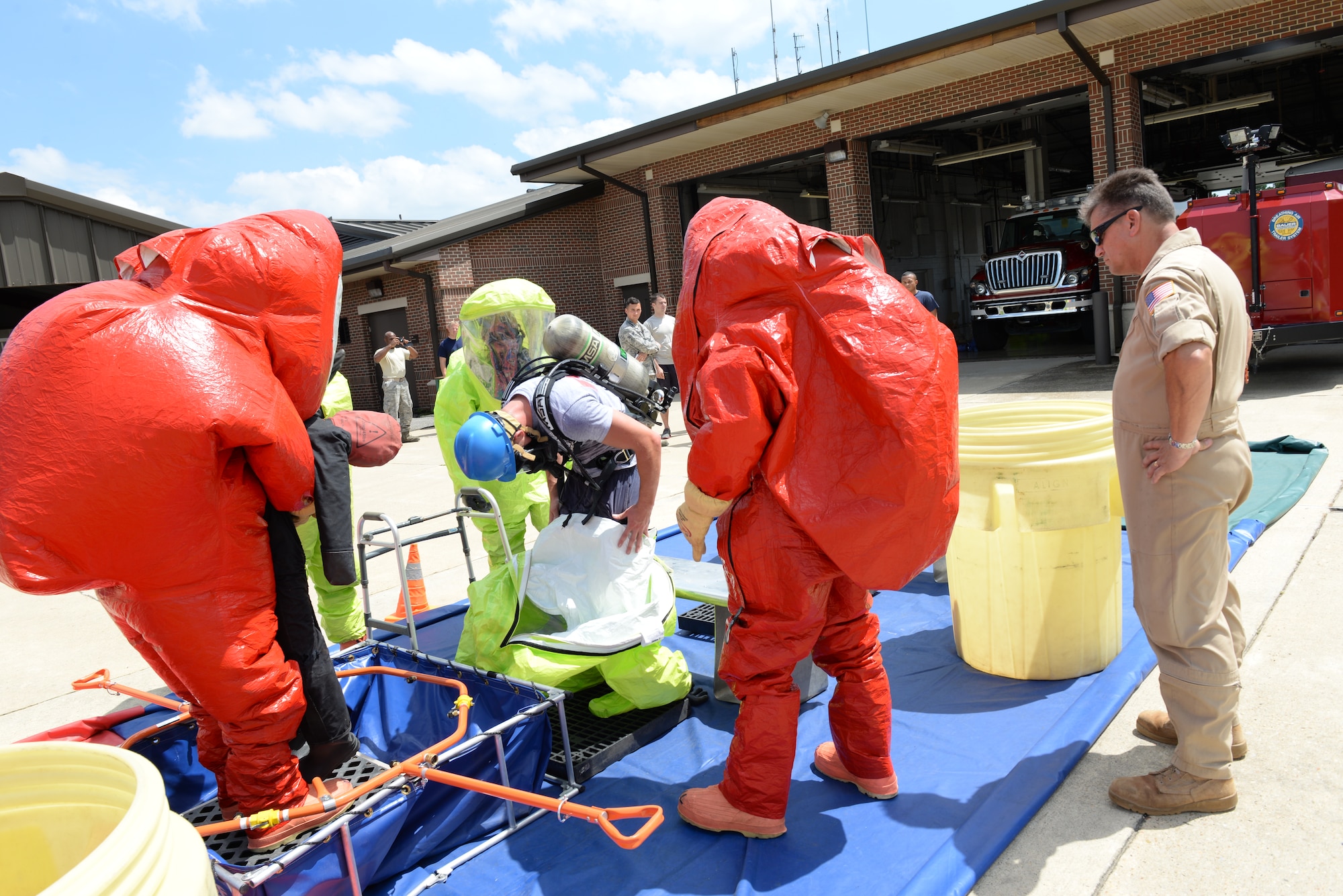 U.S. Service members are instructed on proper removal of personal protective equipment during the final exam of the Hazardous Material Awareness and Operations Training Course held at the station firehouse at Langley Air Force Base, Va., Aug. 13, 2014.  Students were given HAZMAT scenario operations while wearing protective suits. (U.S. Air Force photo by Senior Airman Connor Estes/Released)