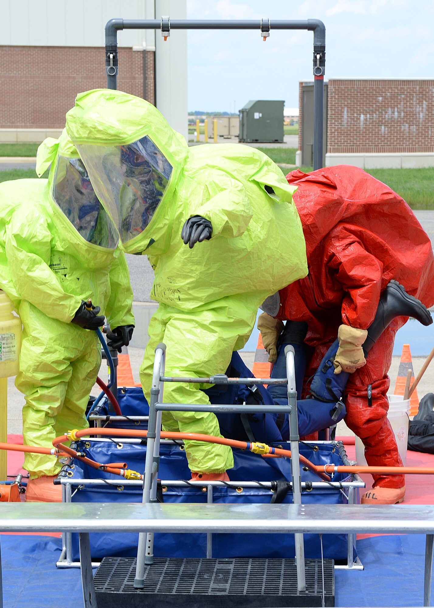 U.S. Service members work together carrying a mannequin through a decontamination station during a Hazardous Materials Awareness and Operations course held at Langley Air Force Base, Va., Aug. 13, 2014. The course helped first responders attain skills needed to properly decontaminate personnel and themselves.  (U.S. Air Force photo by Senior Airman Connor Estes/Released)