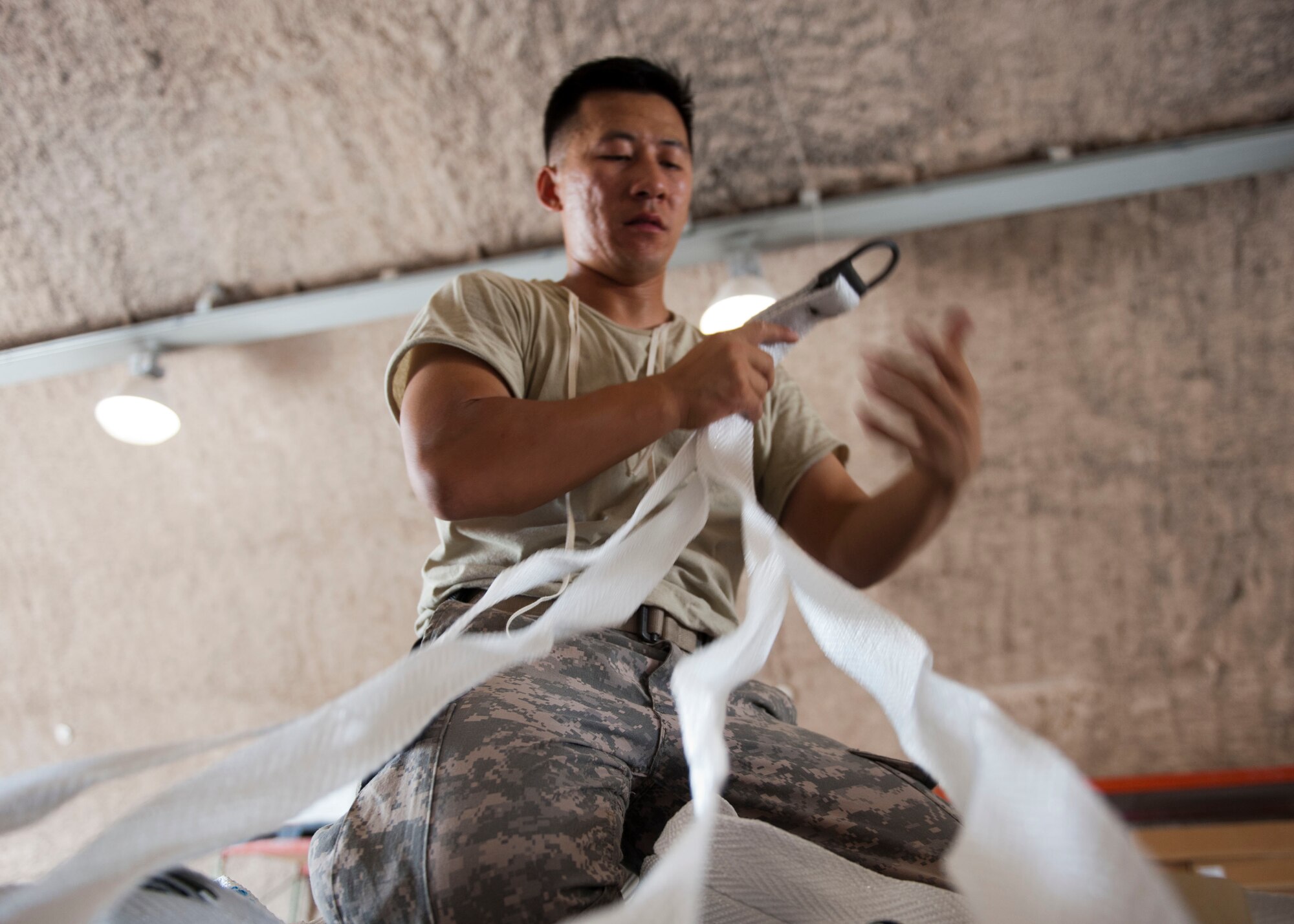 U.S. Army Sgt. Billy Vang, parachutte rigger tightens straps on a pallett at Al Udeid Air Base, Qatar, Aug. 13, 2014. The pallets are being airdropped to displaced citizens in the vicinity of Sinjar, Iraq. Vang is deployed from the 11th Quartermaster Company, Fort Bragg North Carolina and his hometown is Fresno, California. (U.S. Air Force photo by Senior Airman Colin Cates)