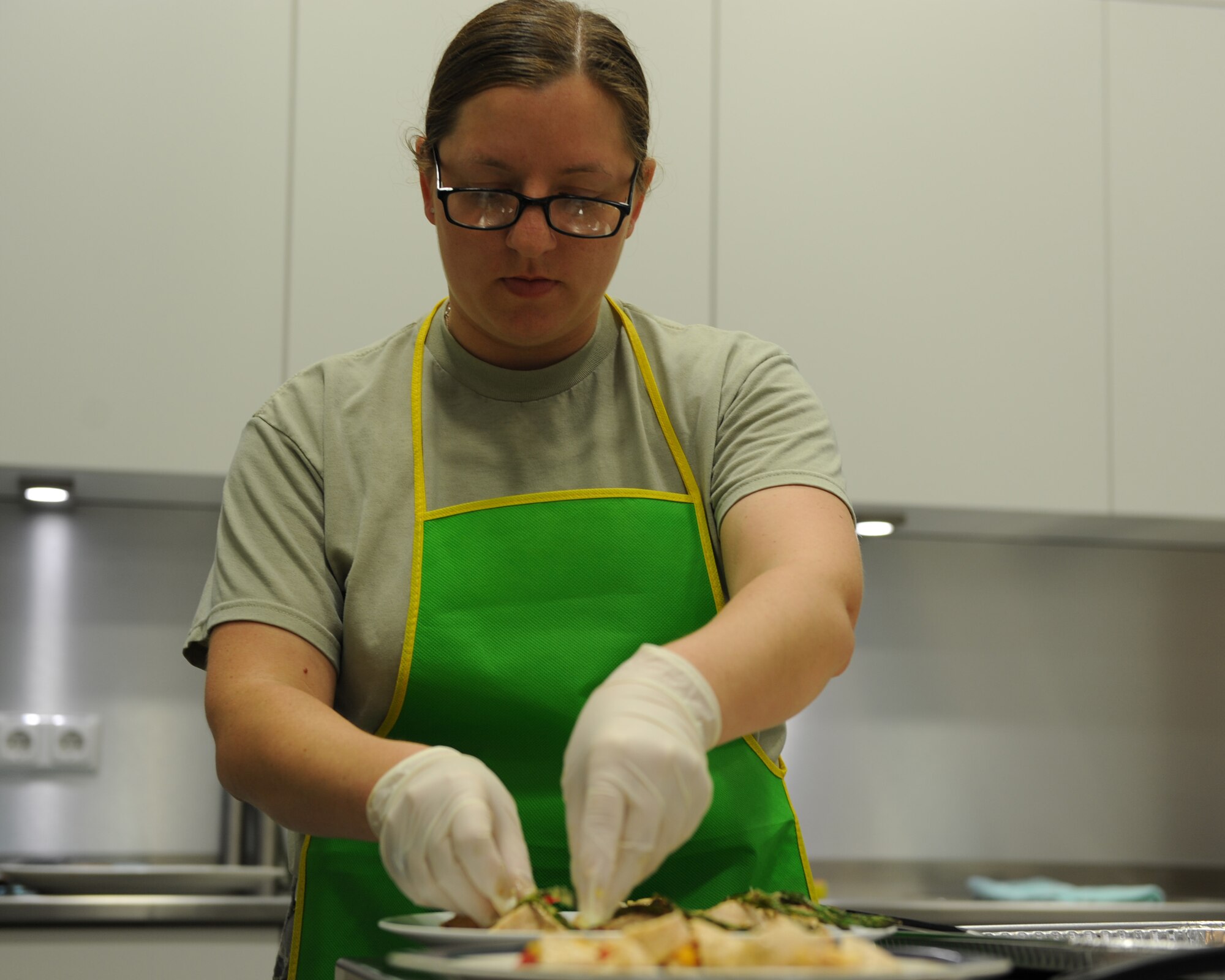 U.S. Air Force Staff Sgt. Natalie Eslinger, 52nd Medical Group training manager, finishes prepping pesto chicken roll-ups during the Ultimate Chef competition Aug. 13, 2014, at Spangdahlem Air Base, Germany. The audience members judged the three contestants’ meals to determine the winner. (U.S. Air Force photo by Airman 1st Class Dylan Nuckolls/Released)