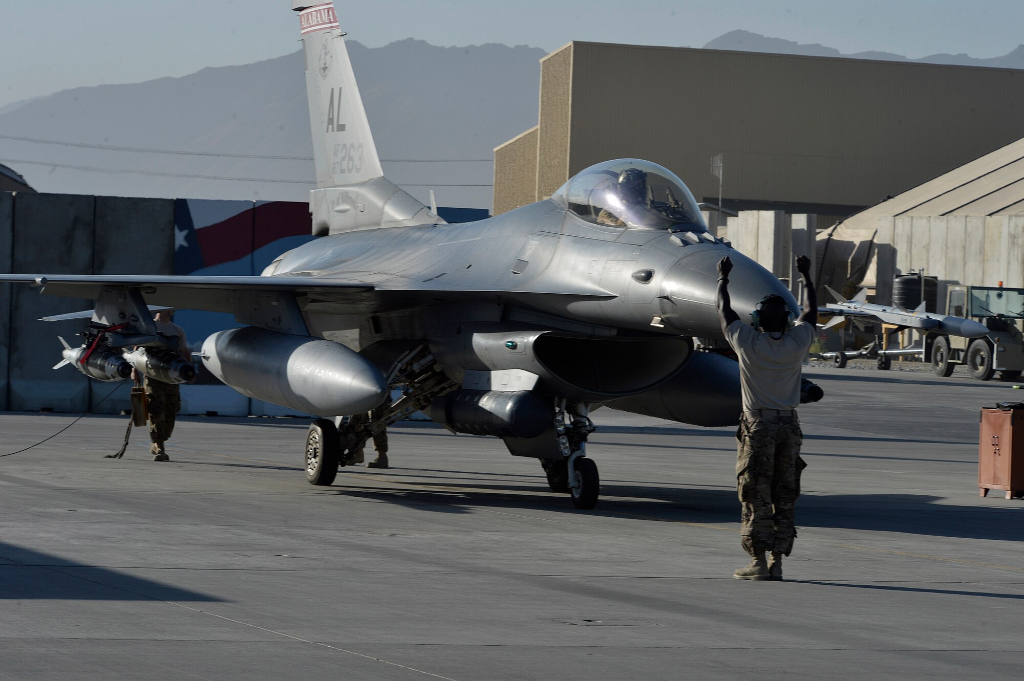 A U.S. Air Force Airman taxis an F-16 “Fighting Falcon” with the 100th Expeditionary Fighter Squadron “Red Tails” at Bagram Airfield, Afghanistan Aug. 7, 2014. The mission of the F-16 “Fighting Falcon” here is to provide tactical air-to-air and air-to-ground support for Operation Enduring Freedom.  The unit is deployed from the 187th Fighter Wing in Montgomery, Ala. (U.S. Air Force photo by Staff Sgt. Evelyn Chavez/Released)