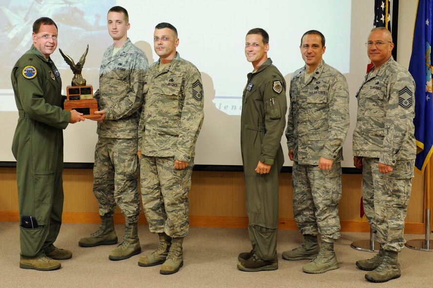 Members from the 67th Aircraft Maintenance Unit receive the Top AMU trophy at the 18th Wing’s 2014 Turkey Shoot on Kadena Air Base, Japan, Aug. 14, 2014. The 67th AMU earned the trophy in this year’s maintenance competition consisting of a timed weapons load competition and inspections on aircraft appearance, correctness of aircraft forms and a timed external fuel tank installation. (U.S. Air Force photo by Senior Airman Maeson Elleman/Released)