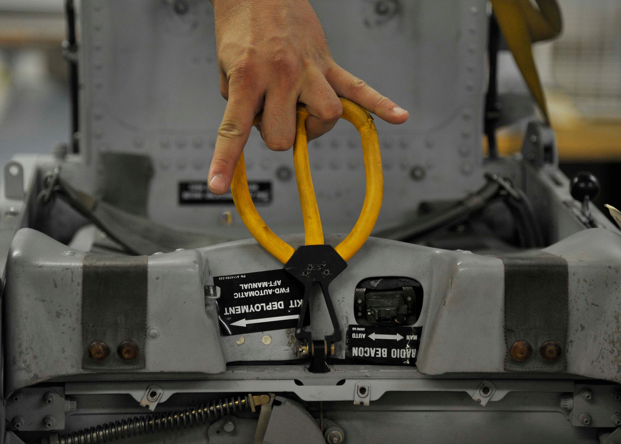U.S. Air Force Senior Airman Jeffrey Bowen, 35th Maintenance Squadron aircrew egress systems journeyman, demonstrates the necessary action to eject from an F-16 Fighting Falcon during an emergency situation at Misawa Air Base, Japan, July 31, 2014. In the ejection process, the pilot will pull the yellow handle, starting an explosive chain of events in the cockpit. This event begins with the canopy blasting off of the aircraft, giving just enough time for the seat itself to rocket out of the framework before putting the pilot through 14 g-forces. Within 2-seconds of initiation, the pilot is separated from the aircraft with the survival kit attached.  (U.S. Air Force photo/Airman 1st Class Patrick S. Ciccarone)