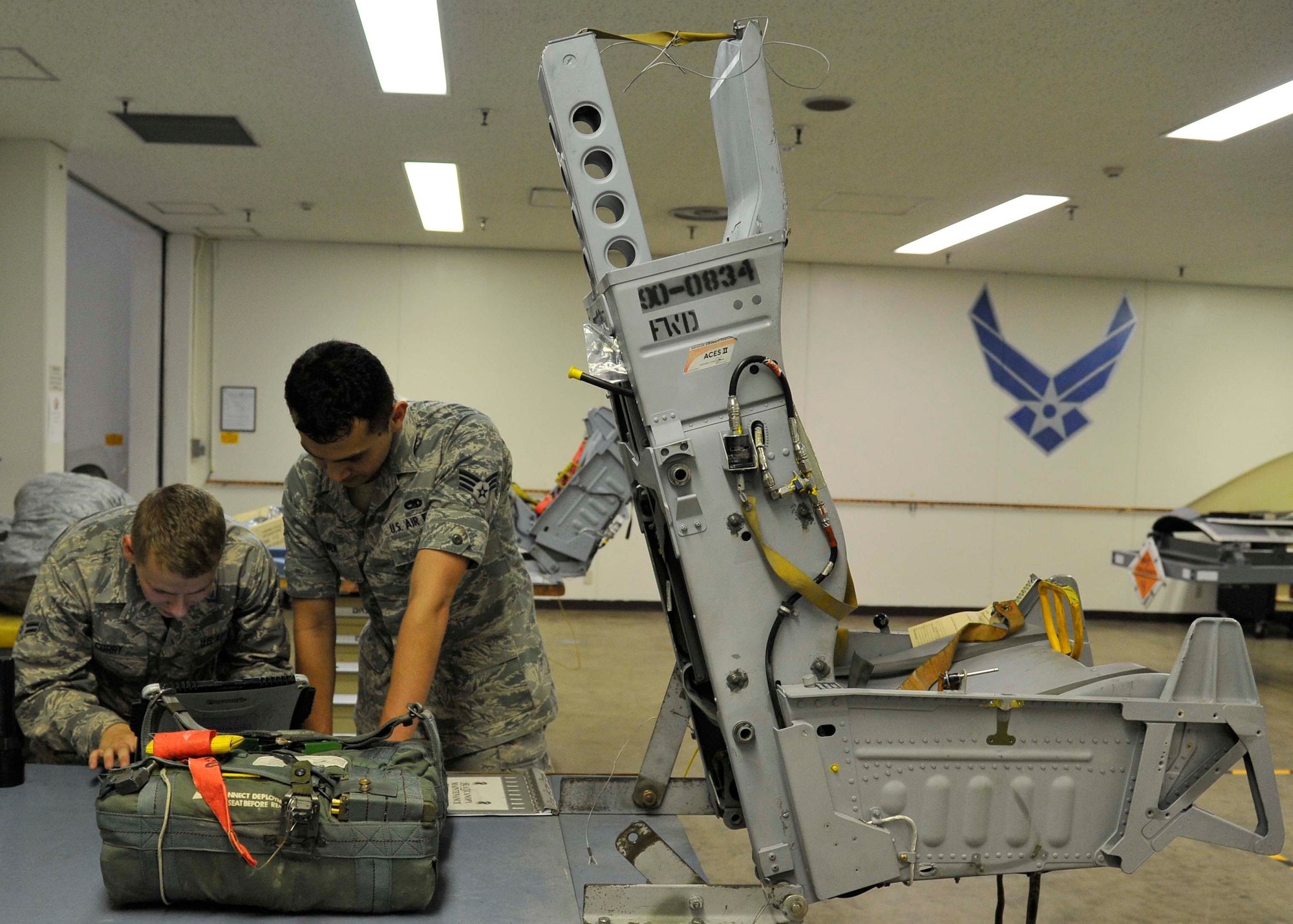 U.S. Air Force Airman 1st Class Peter Curry, 35th Maintenance Squadron aircrew egress systems apprentice and Senior Airman Jeffrey Bowen, 35 MXS aircrew egress systems journeyman, consult a technical order for the installation of an aircrew survival kit at Misawa Air Base, Japan, July 31, 2014. After the Egress team receives the survival kit from the Aircrew Flight Equipment section, they install it into an F-16 Fighting Falcon’s ejection seat. (U.S. Air Force photo/Airman 1st Class Patrick S. Ciccarone)