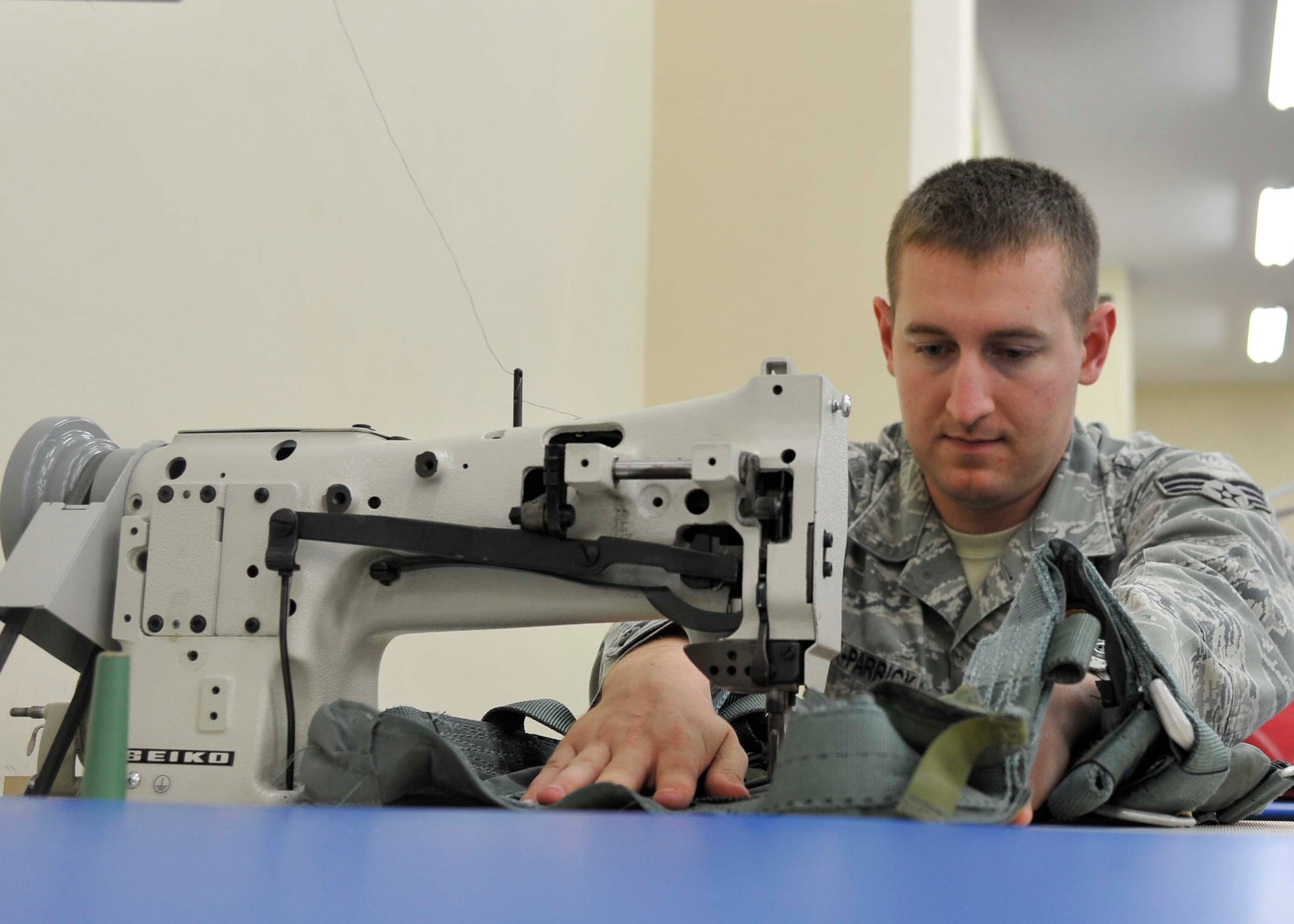 U.S. Air Force Senior Airman Joshua Clark-Parrick, 35th Operations Support Squadron Aircrew Flight Equipment journeyman, sews together metal buckles to a parachute harness at Misawa Air Base, Japan, July 31, 2014. Among the items on the harness are: survival kits, first-aid kits and holsters for weapons to be used in case of an emergency situation. (U.S. Air Force photo/Airman 1st Class Patrick S. Ciccarone)