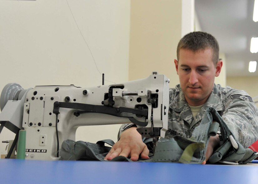 U.S. Air Force Senior Airman Joshua Clark-Parrick, 35th Operations Support Squadron Aircrew Flight Equipment journeyman, sews together metal buckles to a parachute harness at Misawa Air Base, Japan, July 31, 2014. Among the items on the harness are survival kits, first-aid kits and holsters for weapons to be used in case of an emergency situation. (U.S. Air Force photo by Airman 1st Class Patrick S. Ciccarone/Released) 