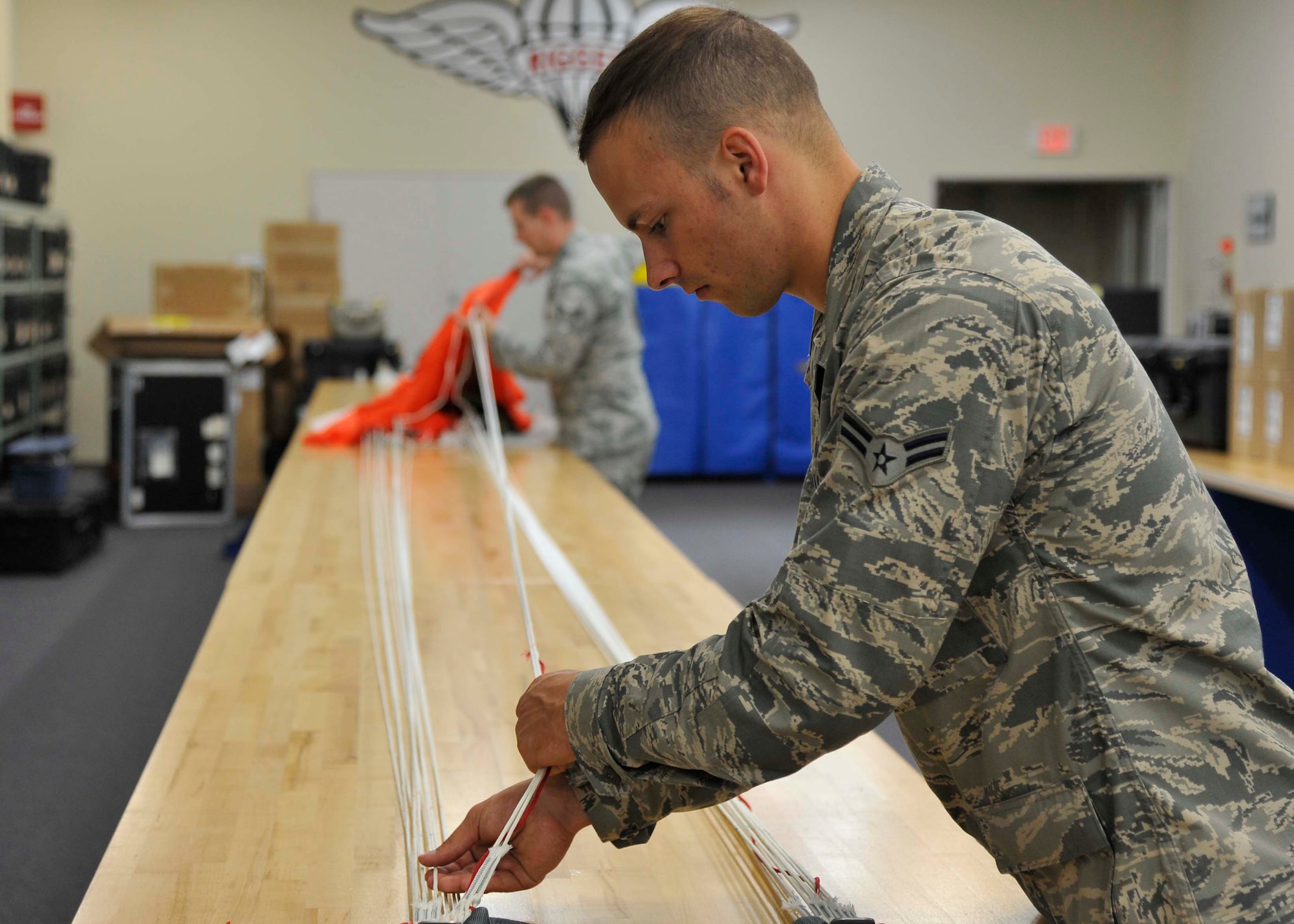 U.S. Air Force Airman 1st Class Parker Taylor, 35th Operations Support Squadron Aircrew Flight Equipment apprentice and Senior Airman Joshua Clark-Parrick, 35 OSS AFE journeyman, untangle a parachute’s suspension lines at Misawa Air Base, Japan, July 31, 2014. Before stowing the parachute into a container, the lines need to be separated and drawn taut, allowing proper folding of the chute. (U.S. Air Force photo/Airman 1st Class Patrick S. Ciccarone)