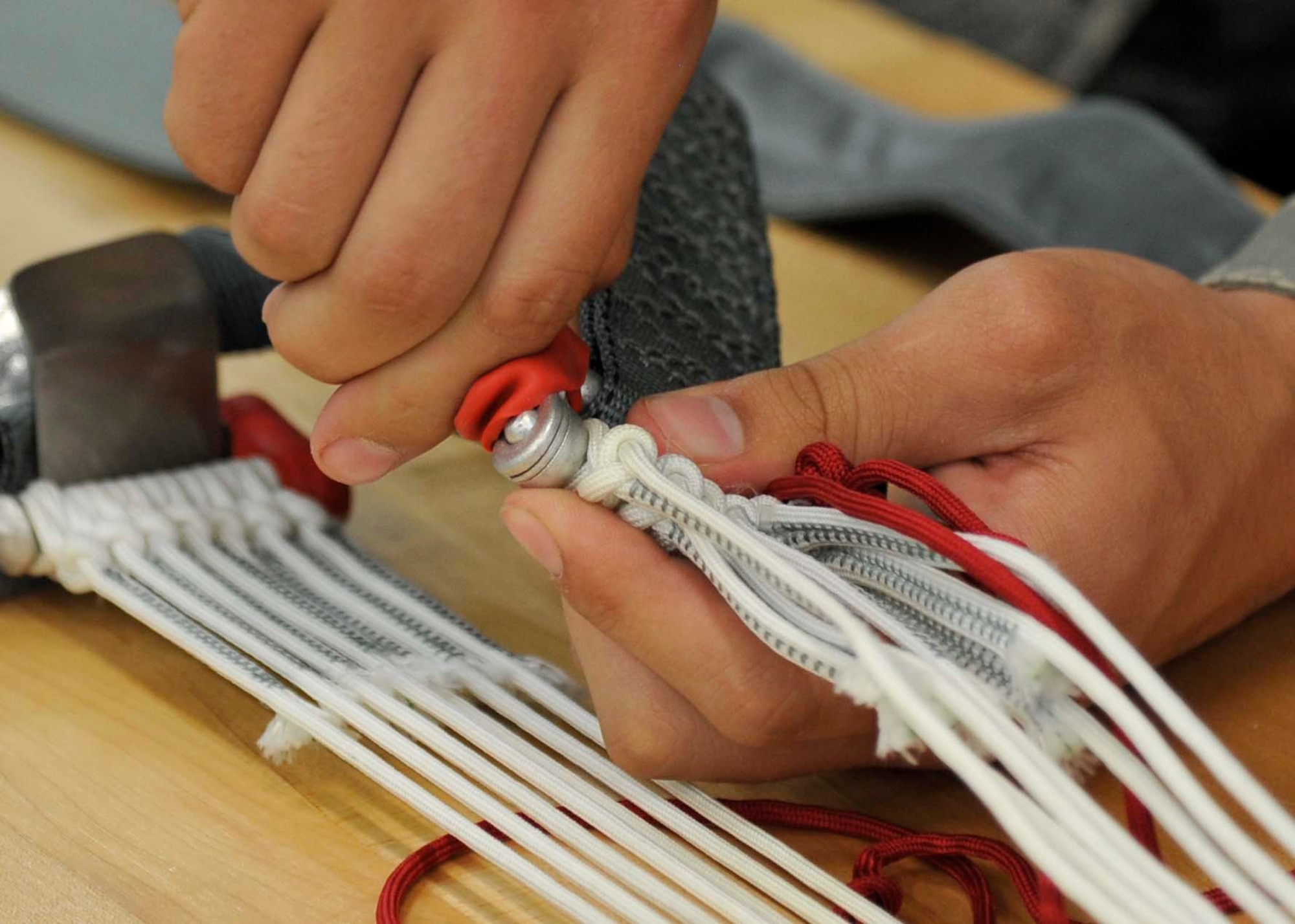 U.S. Air Force Airman 1st Class Parker Taylor, 35th Operations Support Squadron Aircrew Flight Equipment apprentice, secures a parachute’s suspension lines to a harness at Misawa Air Base, Japan, July 31, 2014. During this step in the packing process, Taylor separates and weighs the suspension lines and connects them to a harness positioned toward the opposite end of the chute. (U.S. Air Force photo/Airman 1st Class Patrick S. Ciccarone)