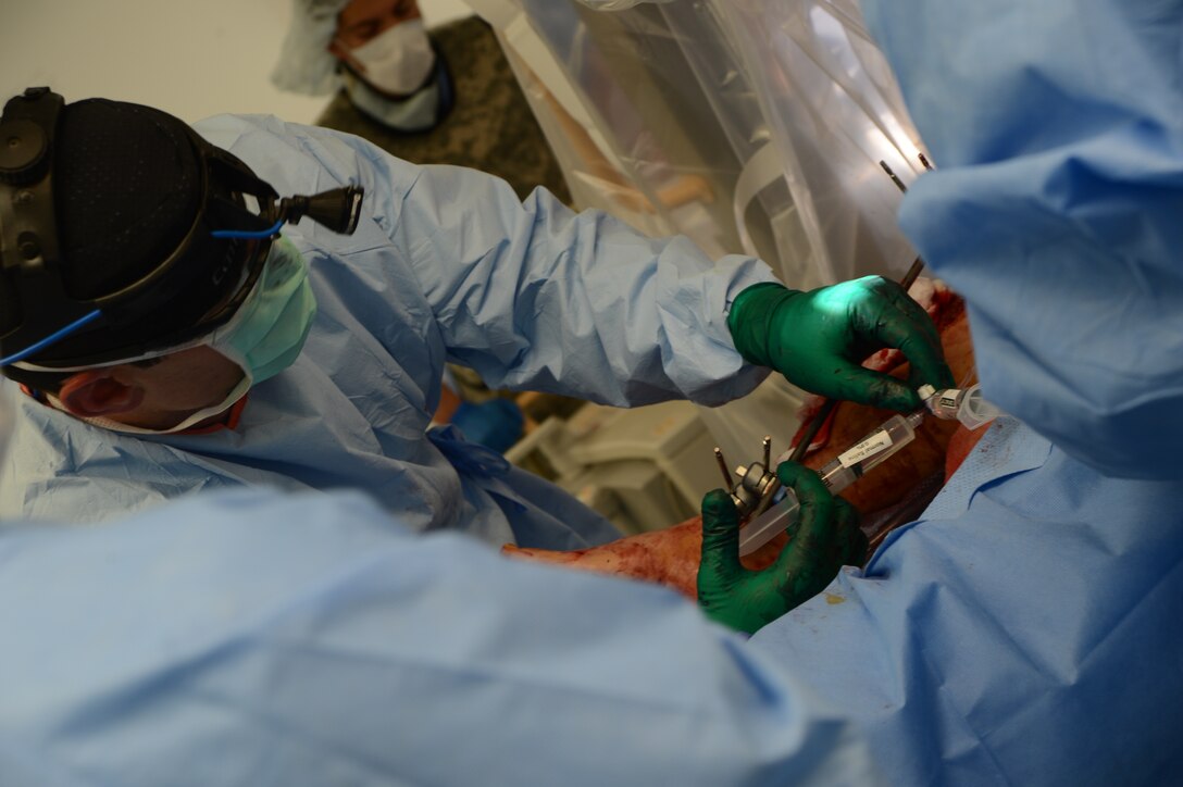 U.S. Air Force Maj. Ryan Finnan injects normal saline into the leg of a patient to flush and clean the wound while in the operating room at the Craig Joint Theater Hospital on 
Bagram Airfield, Afghanistan, Aug. 5, 2014. Finnan is an orthopedic surgeon assigned to the 455th Expeditionary Medical Group.