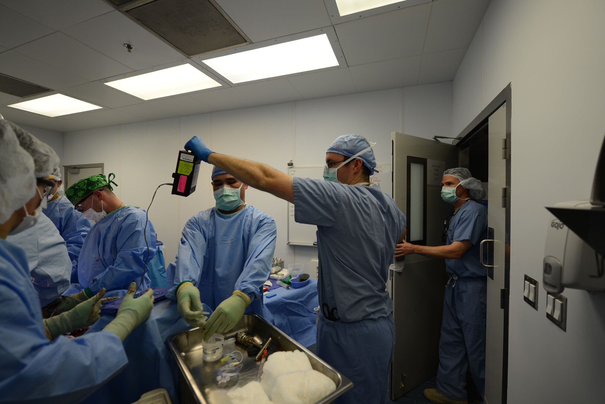 U.S. Air Force Master Sgt. Glenn Dosado (center), a scrub technician assigned to the 455th Expeditionary Medical Group, prepares a syringe for rinsing, while Capt. Brett Price, an operating room nurse, holds a surgical doppler to monitor a patient’s blood flow during a surgery at Craig Joint Theater Hospital, Bagram Airfield, Afghanistan Aug. 5, 2014. Dosada is deployed from Wright-Patterson Air Force Base, Ohio and Price is deployed from Joint Base San Antonio, Texas. (U.S. Air Force photo by Master Sgt. Cohen A. Young/Released)