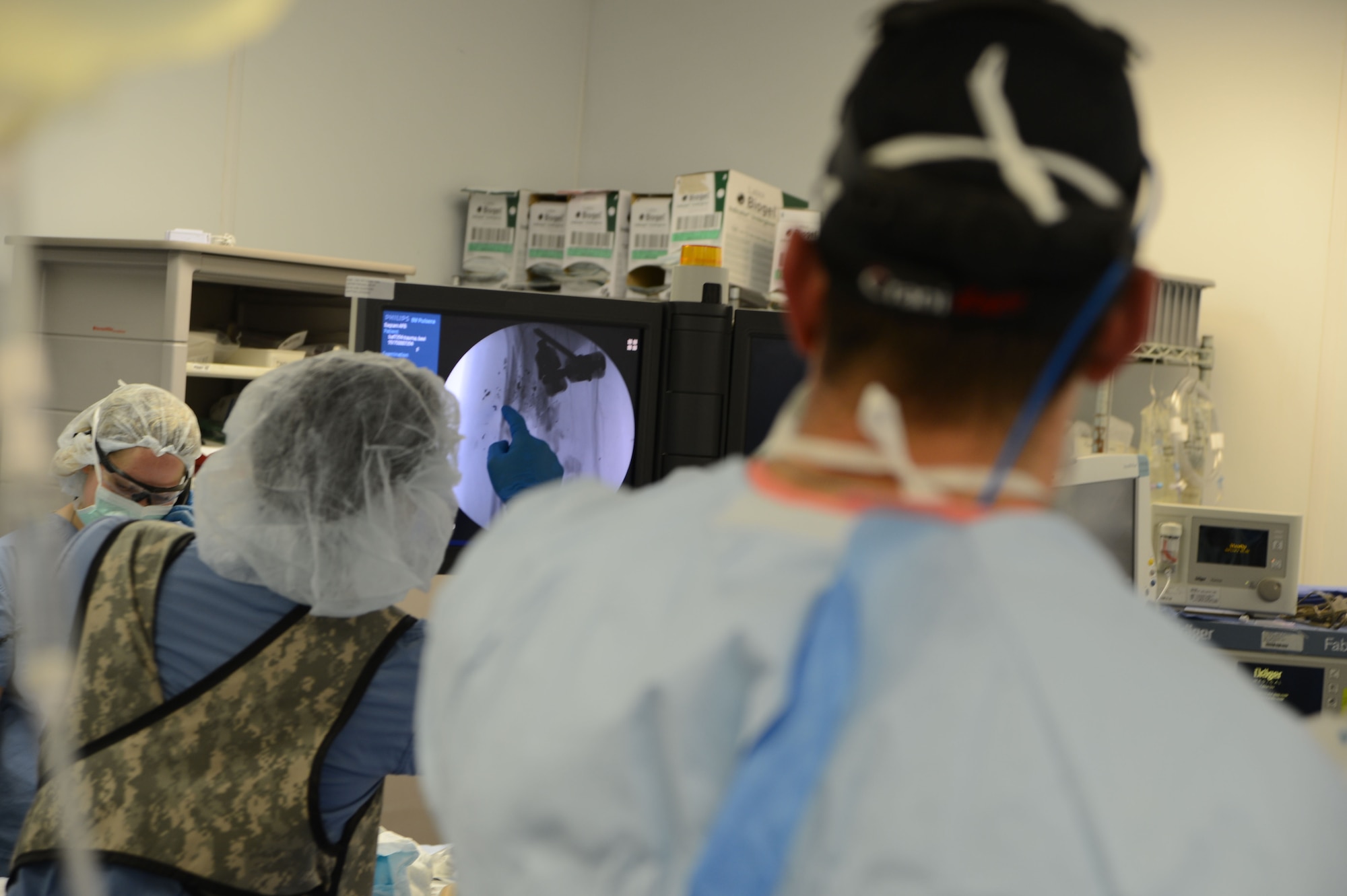 U.S. Air Force Senior Airman Freddy Toruno, 455th Expeditionary Medical Support Squadron diagnostic imaging technologist, points at the point of a fracture on an X-ray to Maj. Ryan Finnan, an orthopedic surgeon, during a surgery on a patient in an operating room of the Craig Joint Theater Hospital, Bagram Airfield, Afghanistan, Aug. 5, 2014. The medical staff of CJTH and 159th Combat Aviation Brigade, “DUSTOFF,” administered emergency care to victims involved in a mass casualty event. Finnan is deployed from the Center for the Sustainment of Trauma and Readiness Skills in Cincinnati, Ohio. (U.S. Air Force photo by Master Sgt. Cohen A. Young/Released)