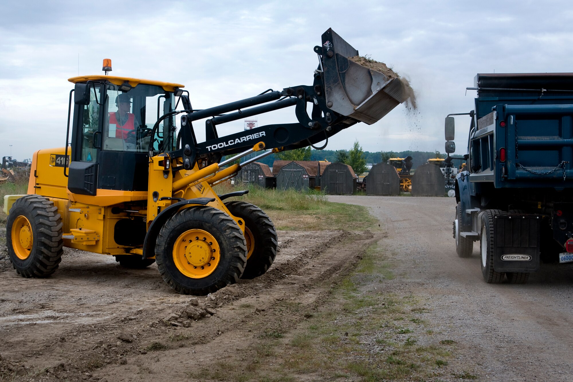 Senior Airman Thomas White, 434th Civil Engineer Squadron pavements and construction apprentice, uses a front end loader to transfer earth into a dump truck during construction of an explosive ordnance disposal training area at Grissom Air Reserve Base, Ind., Aug. 10, 2014. The site provides an area where Grissom EOD technicians can conduct necessary training. (U.S. Air Force photo/Staff Sgt. Andrew McLaughlin) 
