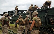 Marines with 8th Engineer Support Battalion, 2nd Marine Logistics Group work with personnel from 9th Engineer Support Battalion, 3rd Marine Logistics Group to climb onto the medium girder bridge to remove panels and pull the bridge into place during bridge assembly training at Camp Lejeune, N.C. Aug. 5, 2014. Marines with 9th ESB cross-trained with 8th ESB to develop their proficiency in bridging. (U.S. Marine Corps photo by Lance Cpl. Kaitlyn Klein/released)


