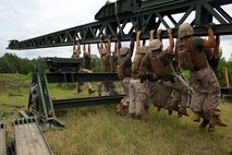 Marines with 8th Engineer Support Battalion, 2nd Marine Logistics Group work with personnel from 9th Engineer Support Battalion, 3rd Marine Logistics Group to pull down on the nose of the medium girder bridge as they lock everything in place during bridge assembly training at Camp Lejeune, N.C. Aug. 5, 2014. This training maintained gap-crossing capabilities and developed proficiency in bridging. (U.S. Marine Corps photo by Lance Cpl. Kaitlyn Klein/released)


