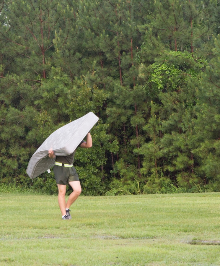 A Marine with 8th Communication Battalion, 2nd Marine Logistics Group, carries a mattress to his company’s truckload of garbage during a Trash Dash aboard Camp Lejeune, North Carolina, July 11, 2014. Six companies from the battalion competed to collect the most trash from the French Creek area. The company that collected the most trash was rewarded with a three-day weekend. (U.S. Marine Corps photo by Pfc. Lucas J. Hopkins/Released).