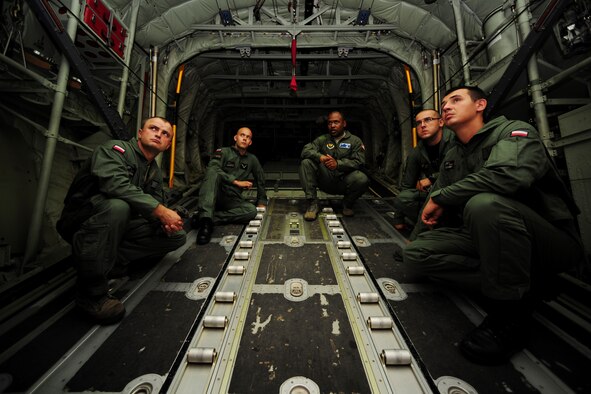 Master Sgt. Chris Minnifield, center right, discusses the finer points of C-130 Hercules mass container delivery airdrop operations with Polish air force service members Aug. 11, 2014, at Powidz Air Base, Poland. The bilateral training was to prepare Polish forces to conduct equipment and supply delivery missions to Iraq. Minnifield is a 37th Airlift Squadron loadmaster. (U.S. Air Force photo/Staff Sgt. Jarad A. Denton)