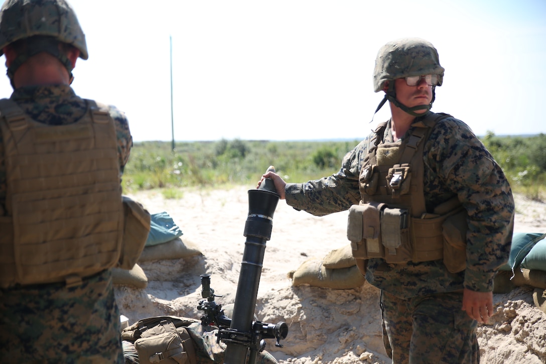 Lance Cpl. Brian Brodman and a mortarman with Weapons Company, 1st Battalion, 24th Marine Regiment hangs a round in the tube before dropping to fire at simulated targets down range as part of an indirect-fire weapons integration exercise Aug. 15, 2014, in Camp Lejeune, N.C. at exercise Heavy Metal 14. Before mortars are fired, mortarmen must wait for the fire direction center to give the signal to fire after each gun has confirmed that their target is properly sighted in.