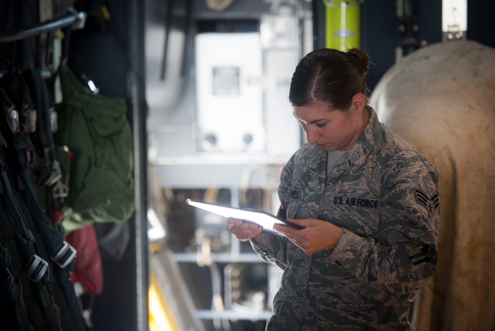 Senior Airman Katie Powell, 374th Operations Support Squadron aircrew flight equipment specialist, reviews her paperwork while performing equipment checks on a C-130 Hercules prior to take off during Exercise RED FLAG-Alaska on Aug. 5, 2014 at Joint Base Elmendorf-Richardson, Alaska. AFE specialists are tasked to inspect oxygen masks and parachutes before every flight. (U.S. Air Force photo by Staff Sgt. Chad C. Strohmeyer/Released)