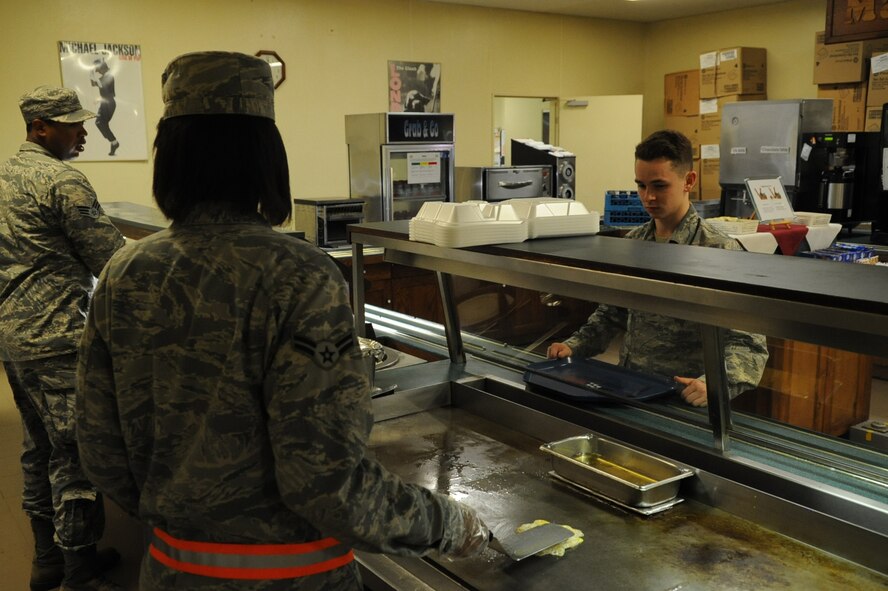 U.S. Air Force Senior Airman Isiah Davis, 18th Force Support Squadron food service specialist (left), and Airman 1st Class Amanda Dotson, 18th FSS food service specialist (middle), prepare food for a customer at the Marshall Dining Facility on Kadena Air Base, Japan, Aug. 19, 2014. The dining facility has late night hours from 10 p.m. to 12:30 a.m. every day to accomodate those who work midnight shifts.  (U.S. Air Force photo by Airman 1st Class Zackary A. Henry)