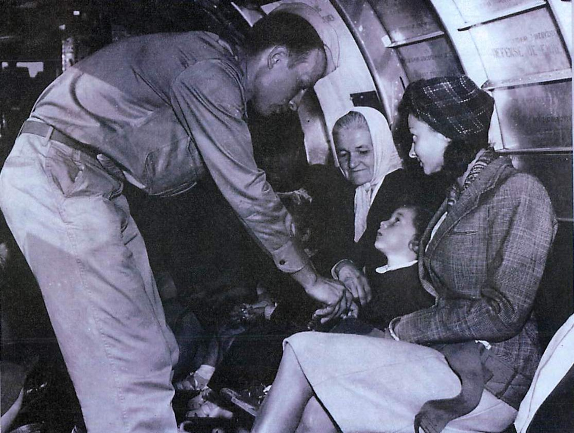 An airman checks the safety belts of his passengers prior to take-off. These passengers are French citizens who were exiled during the war and are finally able to return home. (U.S. Air Force photo)