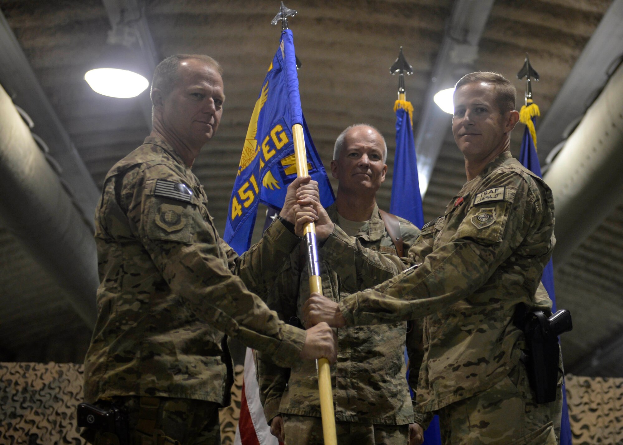 U.S. Air Force Col. Scott Campbell (right) passes the 451st Air Expeditionary Group guidon to Brig. Gen. Mark Kelly, 455th Air Expeditionary Wing commander, to relinquish command during a change of command ceremony at Kandahar Airfield, Afghanistan Aug. 18, 2014. (U.S. Air Force photo by Staff Sgt. Evelyn Chavez/Released)