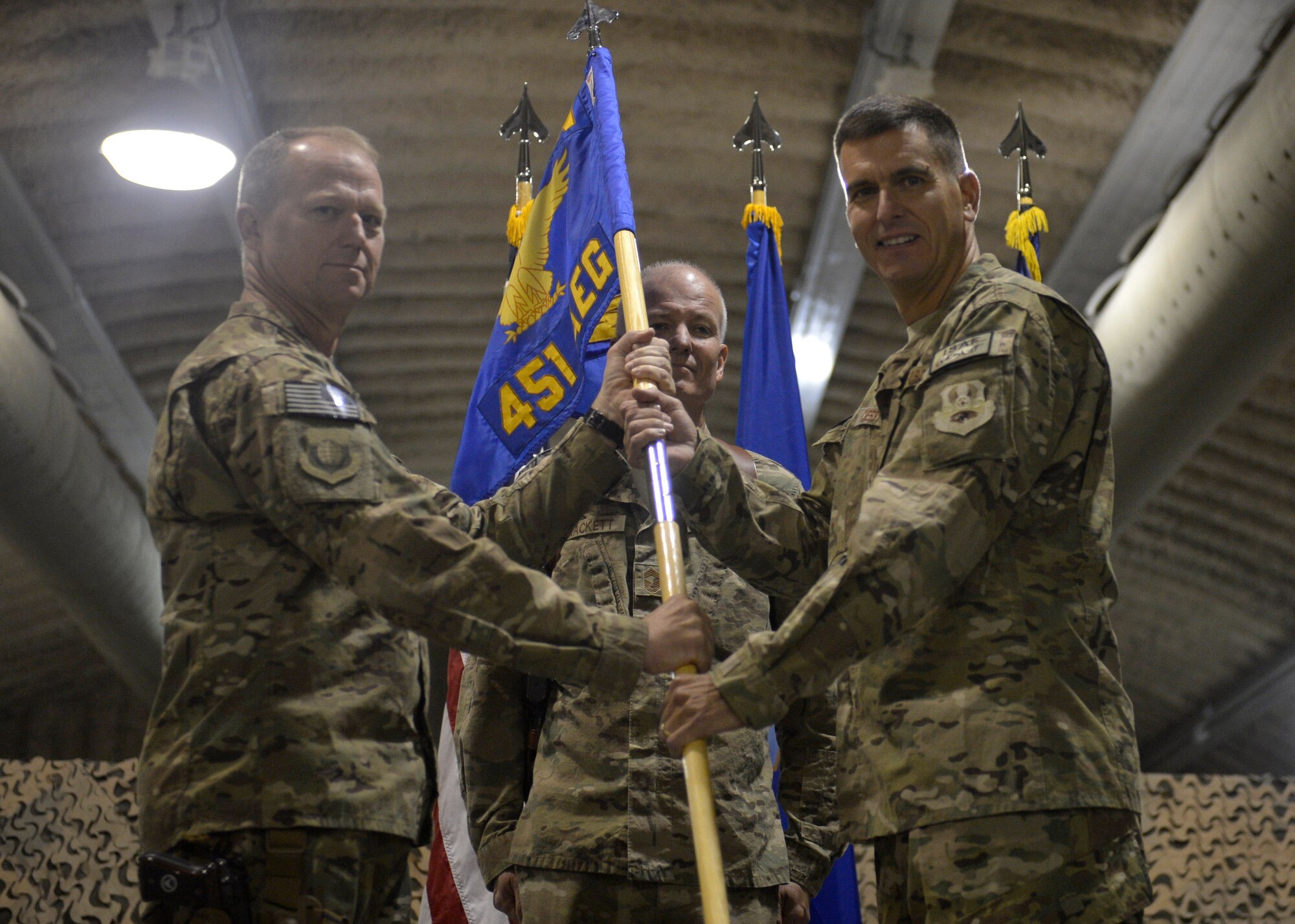 U.S. Air Force Brig. Gen. Mark Kelly, 455th Air Expeditionary Wing commander, passes the 451st Air Expeditionary Group guidon to Col. Rhude Cherry III to assume command during a change of command ceremony at Kandahar Airfield, Afghanistan Aug. 18, 2014. Cherry was the commander for the Joint Planning Support Element, U.S. Transportation Command in Norfolk, Va. (U.S. Air Force photo by Staff Sgt. Evelyn Chavez/Released)