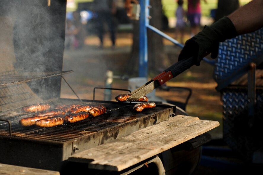 A member of Team Seymour grills sausages during the Summer Time Blast on Aug. 15, 2014, at Seymour Johnson Air Force Base, North Carolina. The event featured fireworks, live music, food, and family games and entertainment. (U.S. Air Force photo/Airman 1st Class Aaron J. Jenne)