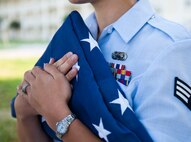 An Airman holds the flag in preparation for reveille at the Eglin Professional Development Center Aug. 14. The current class graduates Aug. 26 from Airman Leadership School as part of their month-long path to becoming a non-commissioned officer. Roughly every two to three weeks ALS begins a new class, averaging seven classes a year. (U.S. Air Force photo/ Tech. Sgt. Jasmin Taylor)