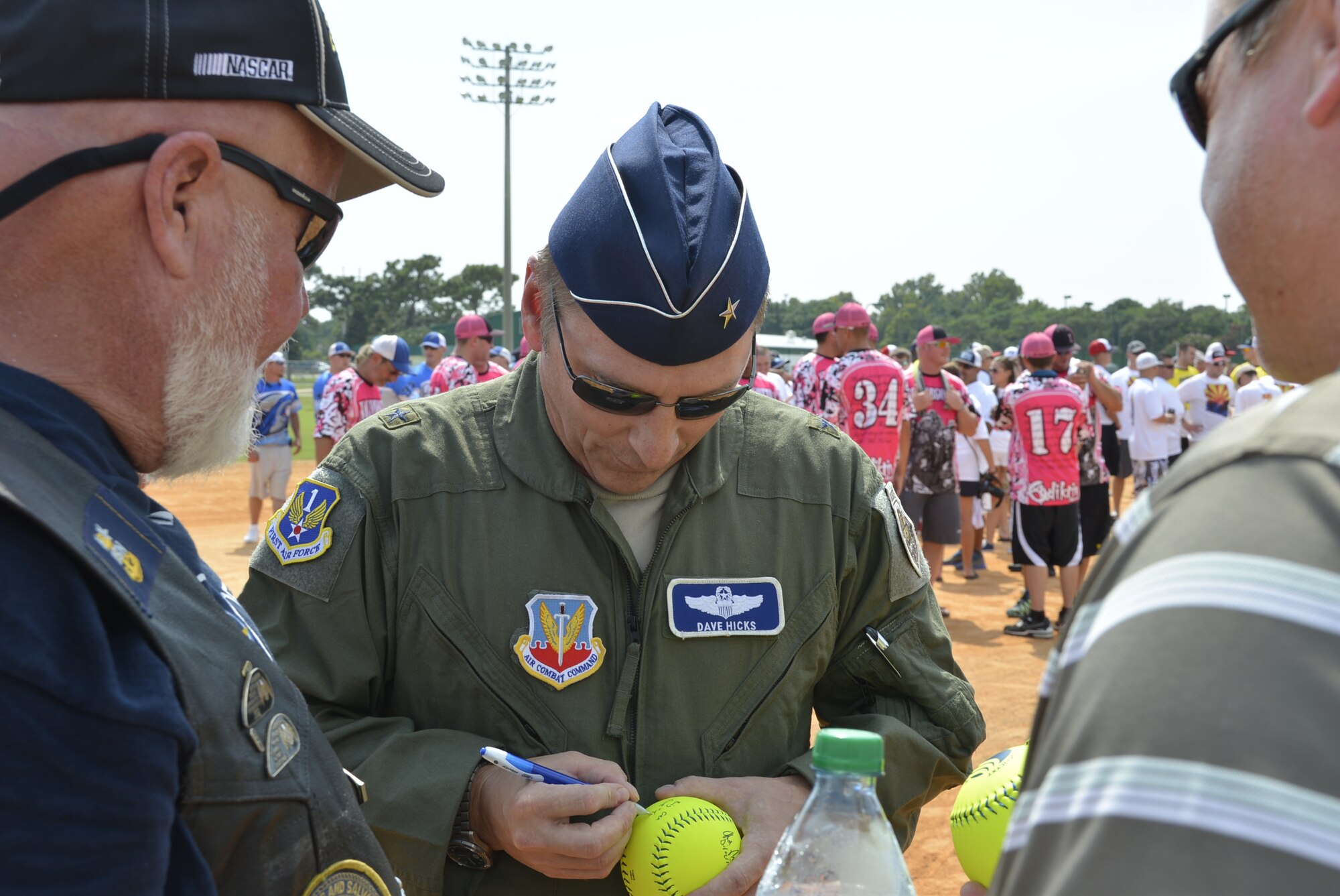 Brig. Gen. David Hicks, Air Forces Northern Vice Commander signs softballs for spectators at the opening ceremonies of the 2014 United States Specialty Sports Association Military World Softball Tournament August 14 at Frank Brown Park. Hicks, along with Chaplain (Capt.) Rudy Olivo, 601st Air and Space Operations Center, and Dan Rowe, Panama City Beach civic leader, tossed the first pitch to open the tournament. The four-day event featured 92 military slow-pitch teams from U.S. military services around the world. (U.S. Photo by Master Sgt. Kurt Skoglund/Released)