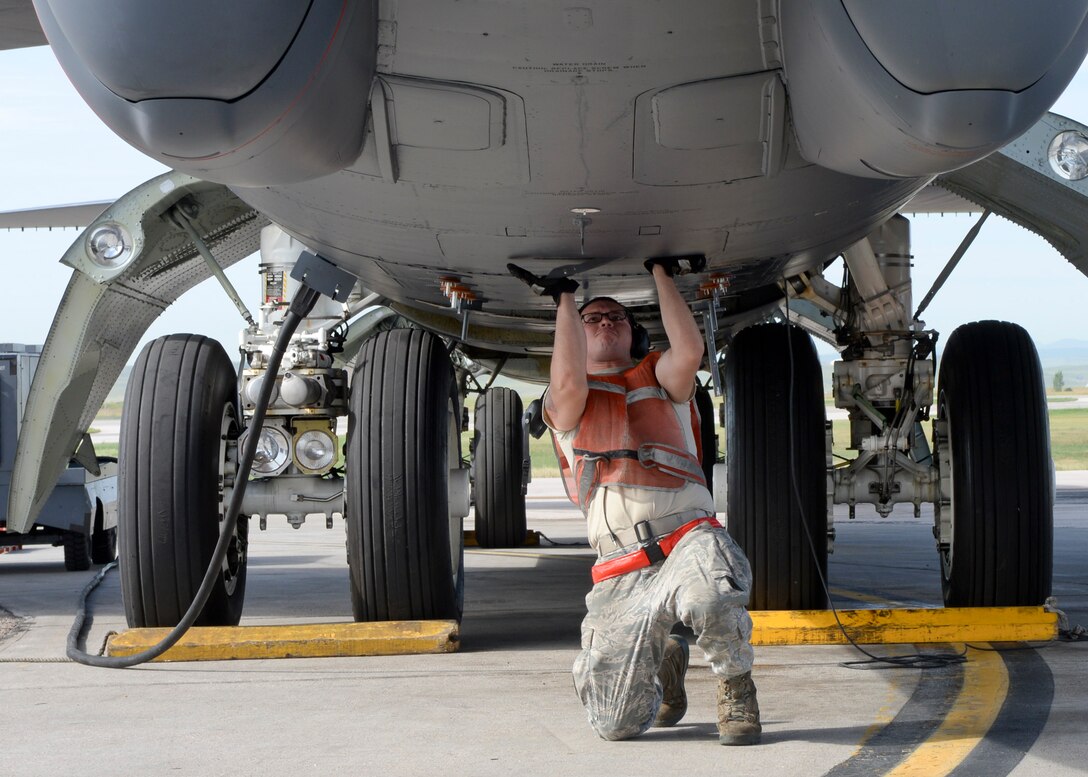 Airman 1st Class Eriberto Gonzalez Gomez, 5th Aircraft Maintenance Squadron crew chief, Minot Air Force Base, N.D., secures flaps underneath a B-52 Stratofortress during launch procedures as part of a standoff weapons integration training exercise on the flightline at Ellsworth AFB, S.D., Aug. 14, 2014. As a crew chief, Gonzalez Gomez is responsible for maintaining and supervising the more than 40 year old aircraft that can carry up to 70,000 pounds of munitions and is capable of flying at high subsonic speeds at altitudes up to 50,000 feet. (U.S. Air Force photo by Senior Airman Anania Tekurio/Released)) 