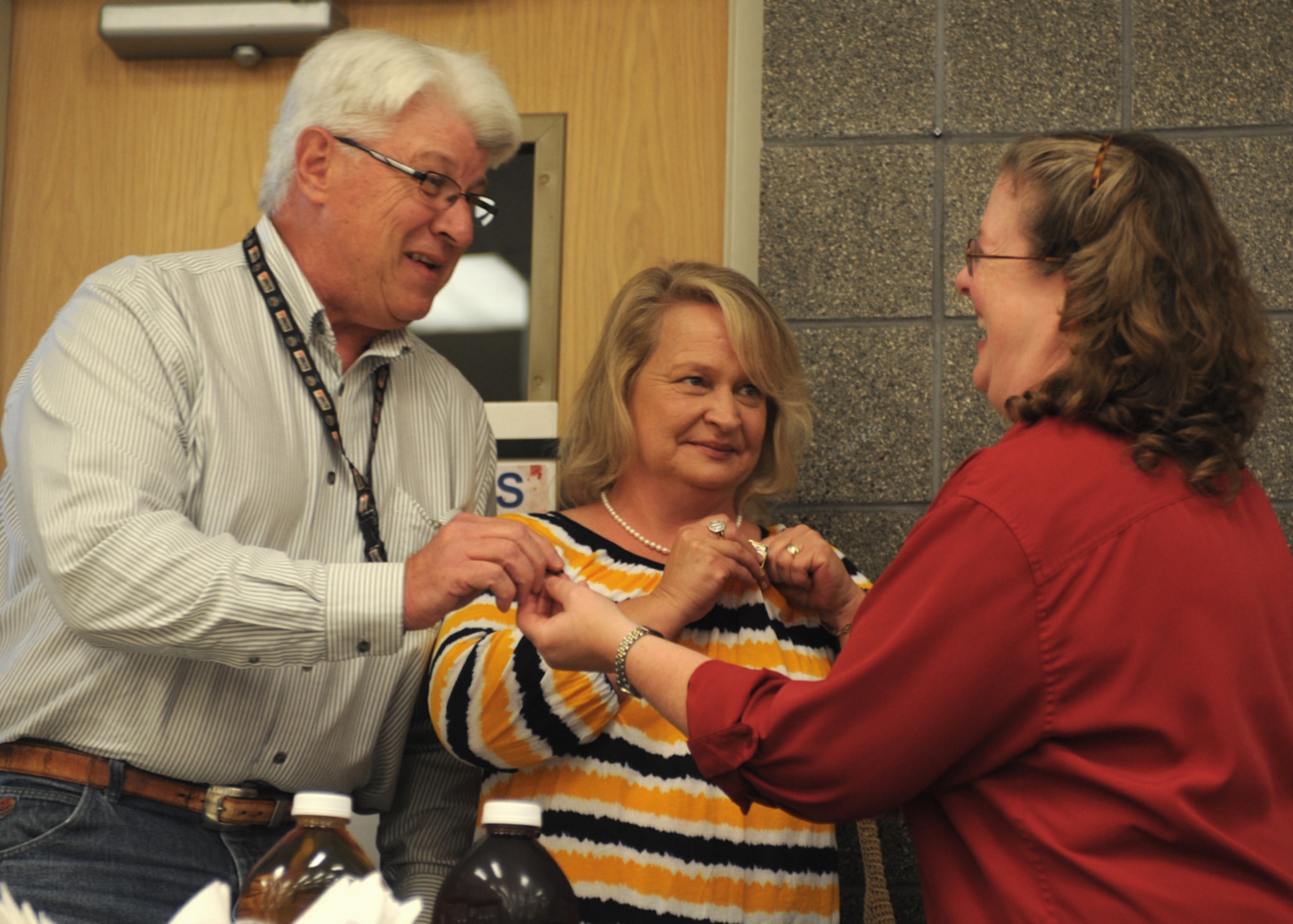 Gerald and Shawn Pelfrey, parents of this year’s Defense Commissary Agency scholarship winner, receive pins from Deborah Dickerson, 27th Special Operations Mission Support Group commissary manager, Aug. 8, 2014 at Cannon Air Force Base, N.M. The Defense Commissary Agency sponsors a scholarship yearly that has given out more than $14 million to help military dependents with the cost of college. (U.S. Air Force photo/Senior Airman Ericka Engblom)