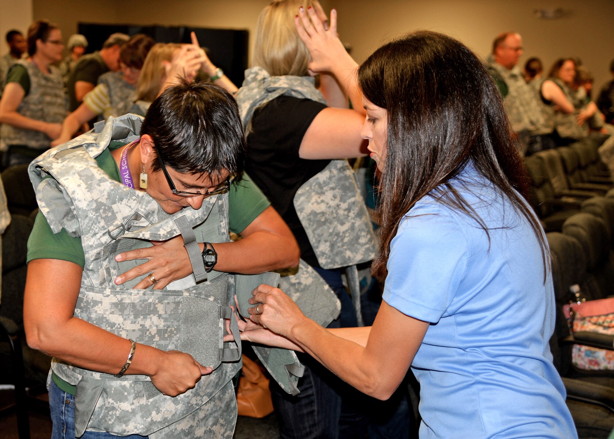 Tricia Bauernfeind, wife of 27th Special Operations Wing commander, Col. Tony Bauernfeind, helps a teacher from the local community properly adjust her flak vest during the Teachers Understanding Deployment Operations program Aug. 12, 2014 at Cannon Air Force Base, N.M. The event was designed to educate local educators and administrators about military operations and the effects deployments have on military children. (U.S. Air Force Photo/Airman 1st Class Chip Slack)