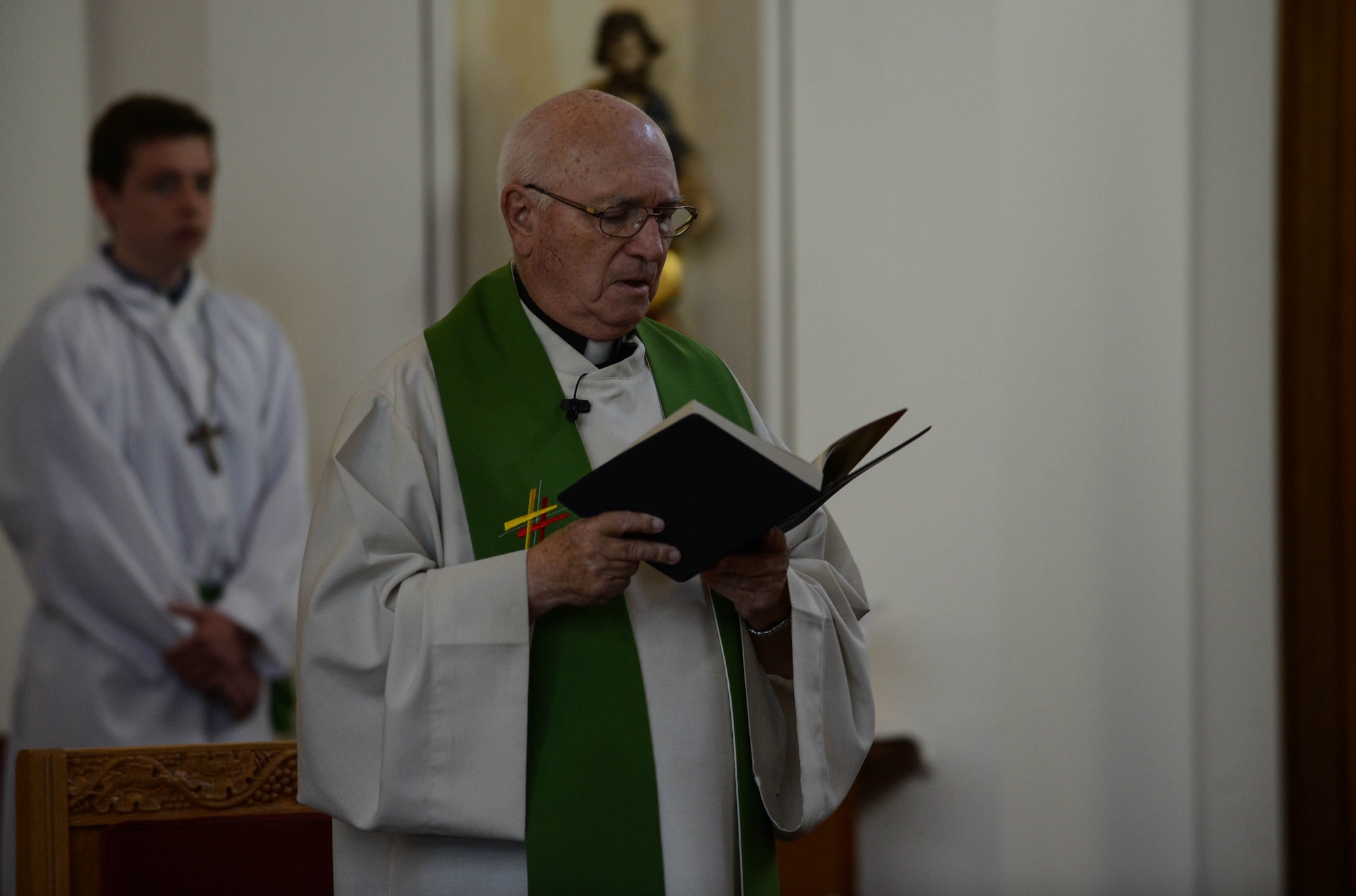 Helmut Pflanz, an auxiliary Catholic priest, reads from the Bible during a service in the chapel at Spangdahlem Air Base, Germany, Aug. 17, 2014.  The chapel provides services to assist people with their spiritual needs. (U.S. Air Force photo by Airman 1st Class Kyle Gese/Released)